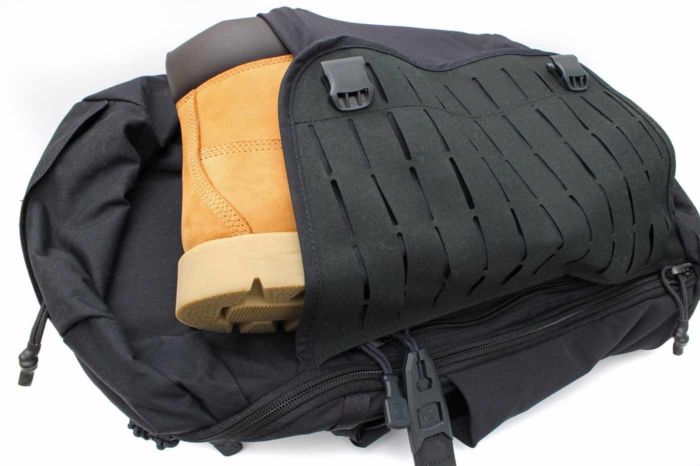 Photo of the central expandable pouch on the Vertx Siege 25L Tactical Backpack. The front pocket is made of stretch nylon that expands to fit larger items such as a helmet, boots, or a rolled-up jacket. Side compression straps with buckles are visible, allowing the user to tighten down the load for stability. MOLLE webbing is reinforced across the pouch face for attaching additional gear. The expandable design adds versatility without increasing bulk when not in use. The rugged fabric and reinforced stitching show durability for tactical or outdoor use. This photo demonstrates the backpack’s adaptability for carrying oversized equipment.