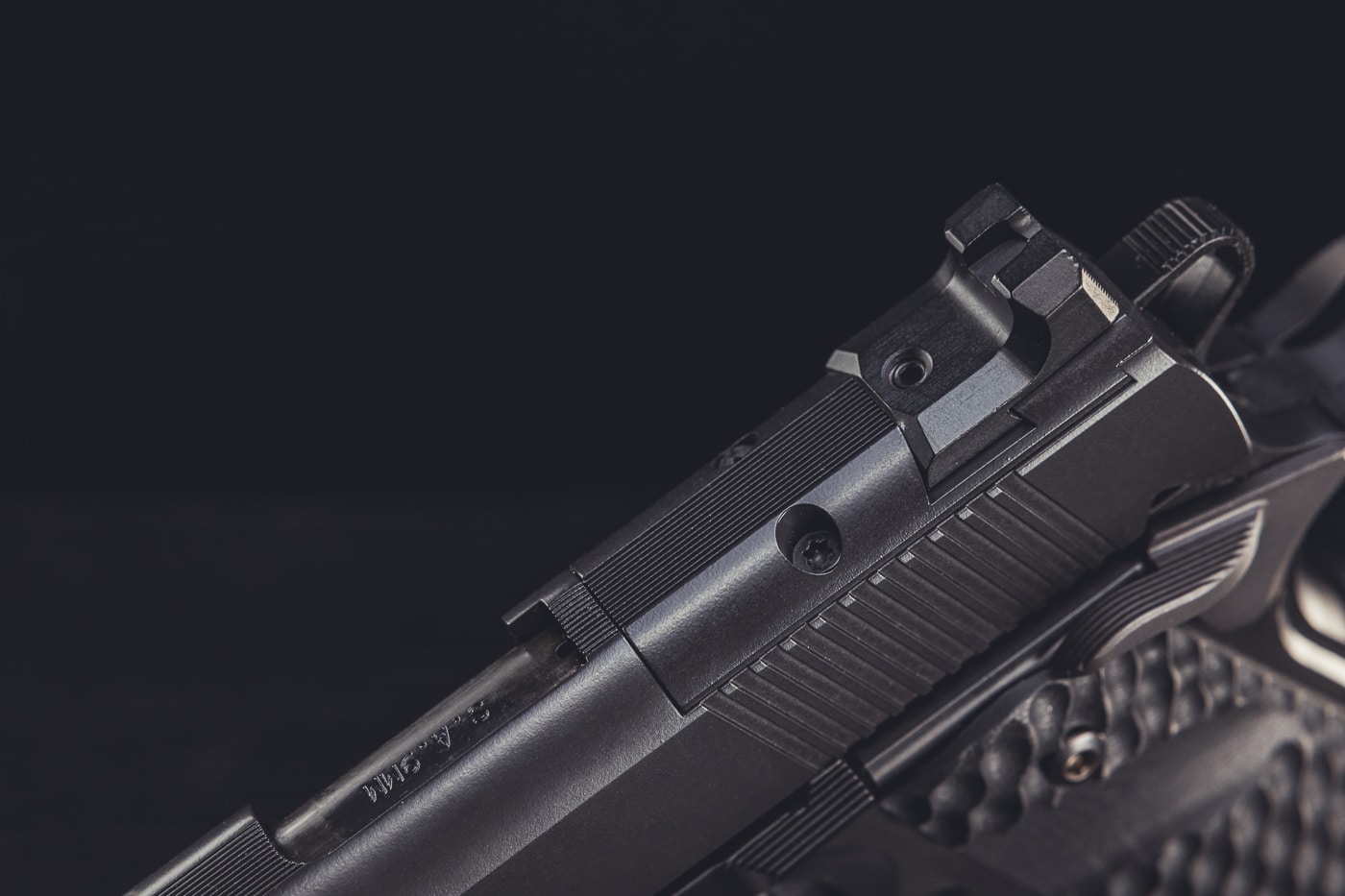 This image provides a close-up view of the Springfield Armory 1911 TRP AOS slide with the cover plate installed over the optic cut. The plate is precision machined to fit flush with the slide, maintaining both the structural integrity and the clean profile of the pistol. Integrated rear sights are visible on the plate, ensuring the handgun remains fully functional with iron sights when no optic is mounted. The matte finish and detailed machining show Springfield’s attention to durability and performance. This component is part of the Agency Optic System, designed to allow quick transitions between red dot sights and traditional sights. The photo emphasizes craftsmanship, flexibility, and the practical engineering behind the TRP AOS platform.