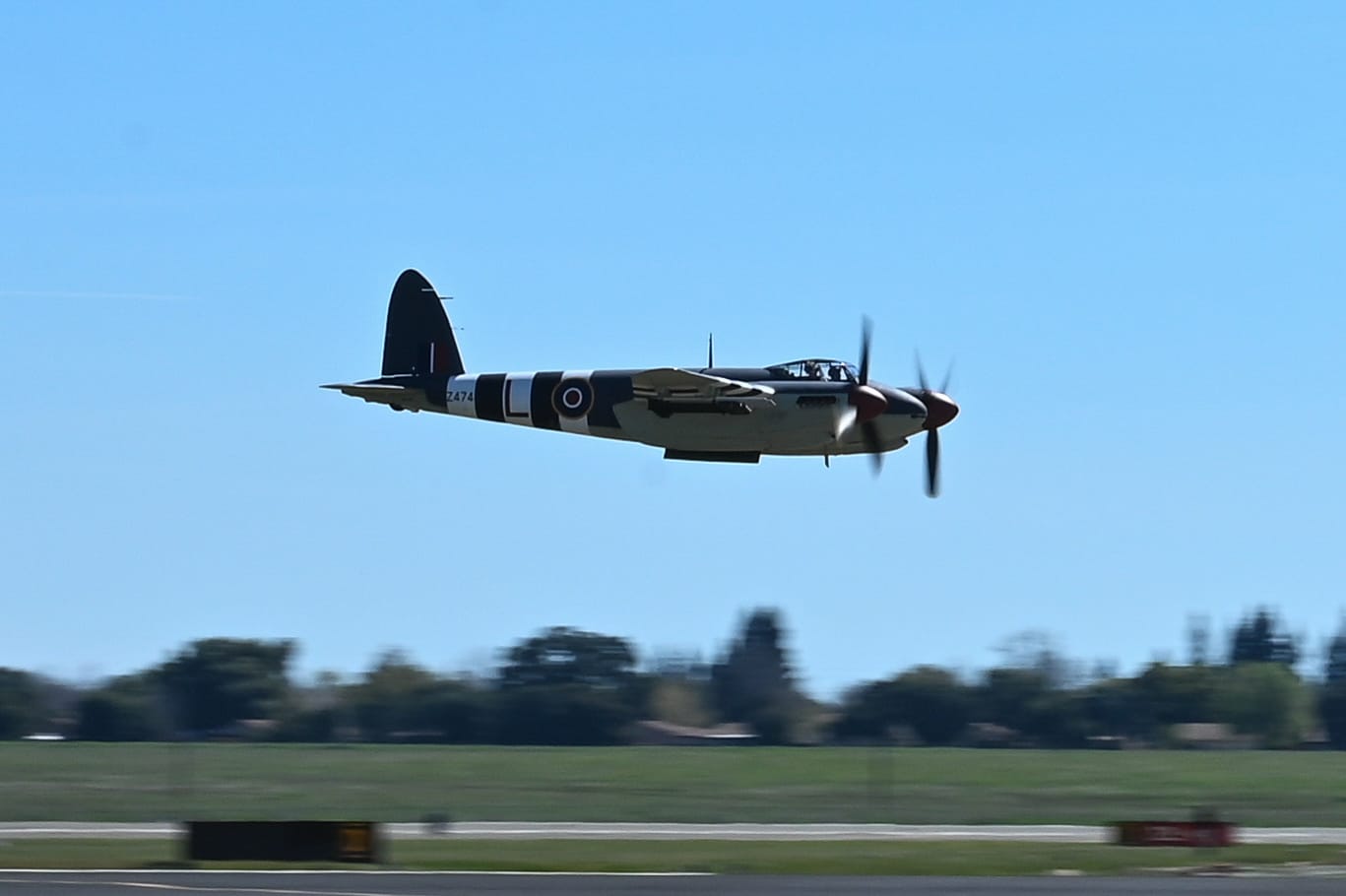 A de Havilland Mosquito aircraft in mid-flight during a demonstration at the California Capital Airshow, Mather, on March 23, 2025. The twin Merlin-powered engines are clearly visible, and the aircraft’s wingspan and fuselage silhouette stand out against a light blue sky. This photograph captures a warbird that, despite being built largely of plywood and balsa, remains one of the most elegant and fast aircraft of its era. The Mosquito is flying at an angle, likely in a turn or banking pass, showing off its agility. Spectators below and possibly other aircraft in the show may be out of frame, but the focus is entirely on the Mosquito’s graceful sweep through the air. This image juxtaposes the vintage warplane with a modern airshow setting, bridging past and present.