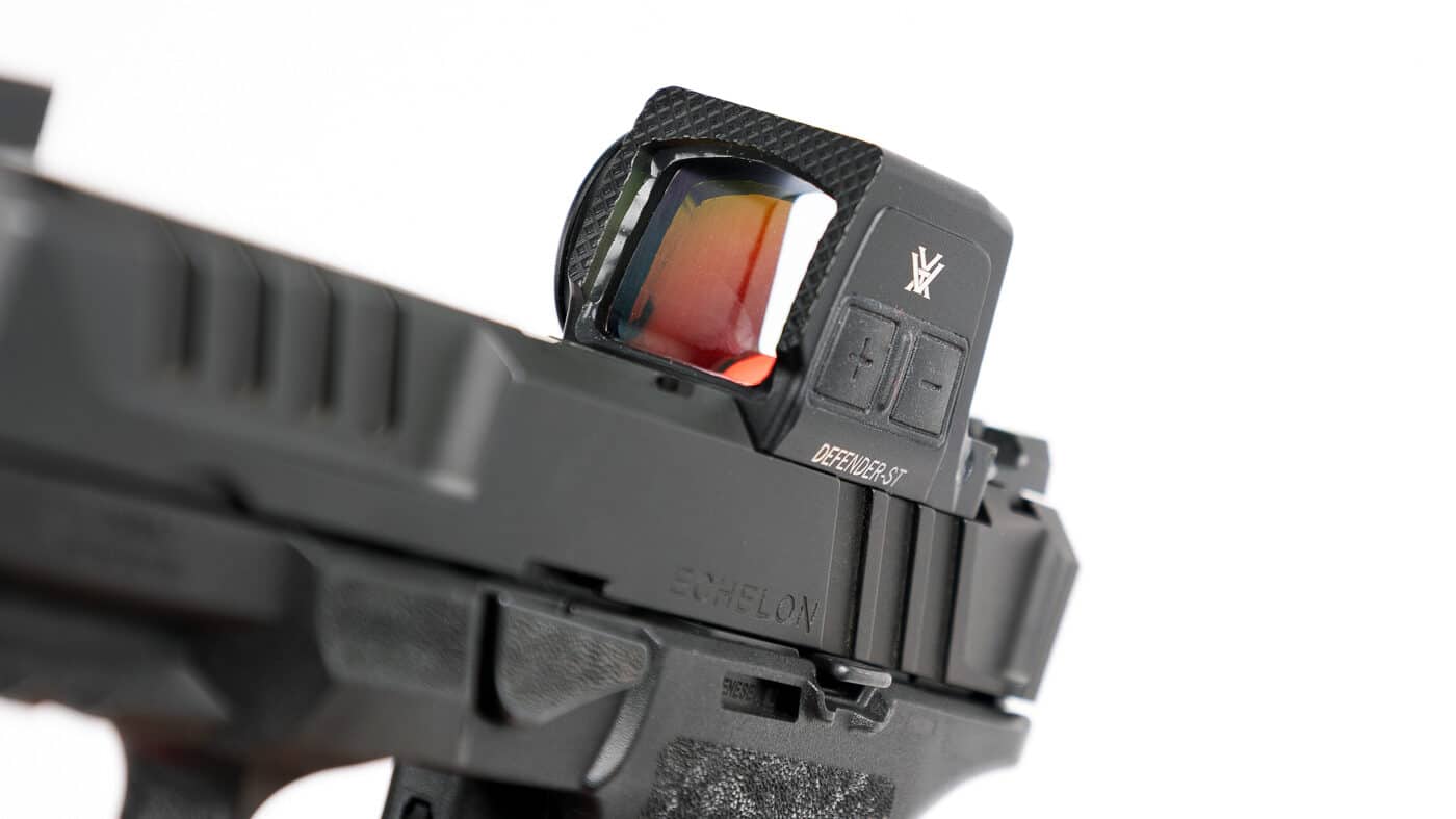Close-up view of the Vortex Defender-ST Enclosed red dot sight highlighting the forward edge of the optic. The front surface features Vortex’s Fast-Rack texturing, a series of machined ridges designed to provide traction for one-handed slide manipulation. This allows shooters to rack the pistol slide against a belt, holster, or hard surface if needed during defensive use. The housing is made of durable 7075 aluminum, ensuring it withstands repeated impact without damage. The optic’s lens is fully enclosed within the body, keeping the emitter protected from dirt and debris. The image emphasizes the rugged build quality and practical utility of the forward design.