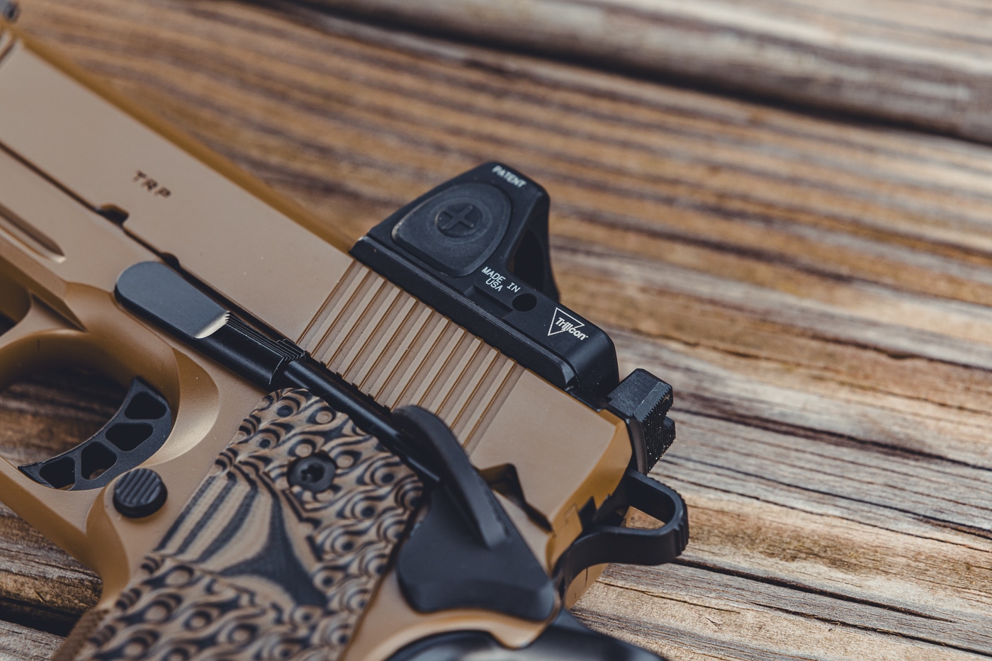 This image shows a close-up of a Springfield Armory 1911 TRP AOS slide with a red dot sight securely mounted. The optic is attached using the Agency Optic System plate, giving it a flush, low-profile fit on the handgun. The slide’s serrations, durable finish, and integrated rear sight are visible in the photo. The red dot optic demonstrates the TRP AOS system’s ability to accept modern optics without custom gunsmithing. This configuration offers shooters faster target acquisition and improved accuracy. The photo highlights the precision machining and flexibility of Springfield’s optics-ready 1911 platform.