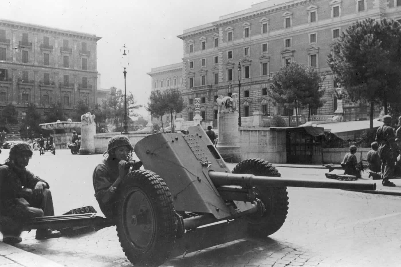 A German 4.2 cm Pak 41 anti-tank gun is shown deployed on an Italian street during World War II. The compact weapon features a tapered squeeze-bore barrel that reduced from 42 mm to 28 mm at the muzzle, dramatically increasing projectile velocity. This design gave the gun strong armor penetration for its size. However, it required tungsten-core ammunition, which was scarce in wartime Germany. The photo shows the gun positioned in an urban setting, prepared to engage Allied vehicles in close quarters. Its limited production and deployment make it one of the rarer German anti-tank weapons of the war.