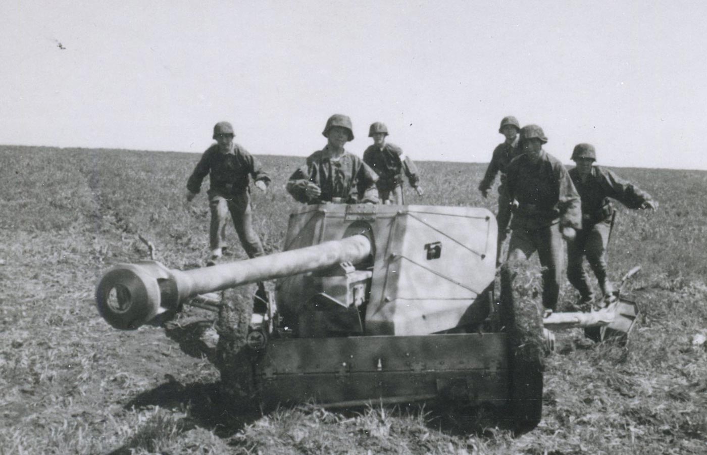 A group of German soldiers operates a 7.5 cm Pak 40 anti-tank gun on the Eastern Front during World War II. The men rush to load and aim the weapon while positioned in a field defense line. The Pak 40, introduced in 1942, could penetrate the armor of most Soviet and Allied tanks at ranges beyond 1,000 meters. This photo illustrates the teamwork required to operate the heavy gun under combat conditions. Sandbags and dirt cover provide partial protection for the crew. The scene highlights the importance of towed artillery in stopping tank assaults.