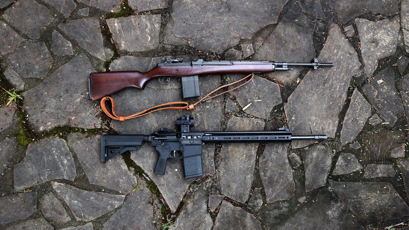 Lead image featuring two .308 rifles positioned next to each other: the Springfield Armory M1A on the left and the SAINT Victor AR-10 on the right. The M1A displays a traditional walnut stock and parkerized steel finish, while the AR-10 shows off its modern black tactical configuration. The background is clean and simple to focus attention on the rifles themselves. This image establishes the central theme of comparing the M1A’s retro craftsmanship with the AR-10’s contemporary design. It visually frames the question of which platform suits different shooting preferences. The photograph supports SEO for terms like “M1A vs AR-10,” “Springfield Armory,” and “.308 semi-auto rifles.” It helps readers immediately understand that this article is about evaluating both rifles’ design philosophies and performance potential.