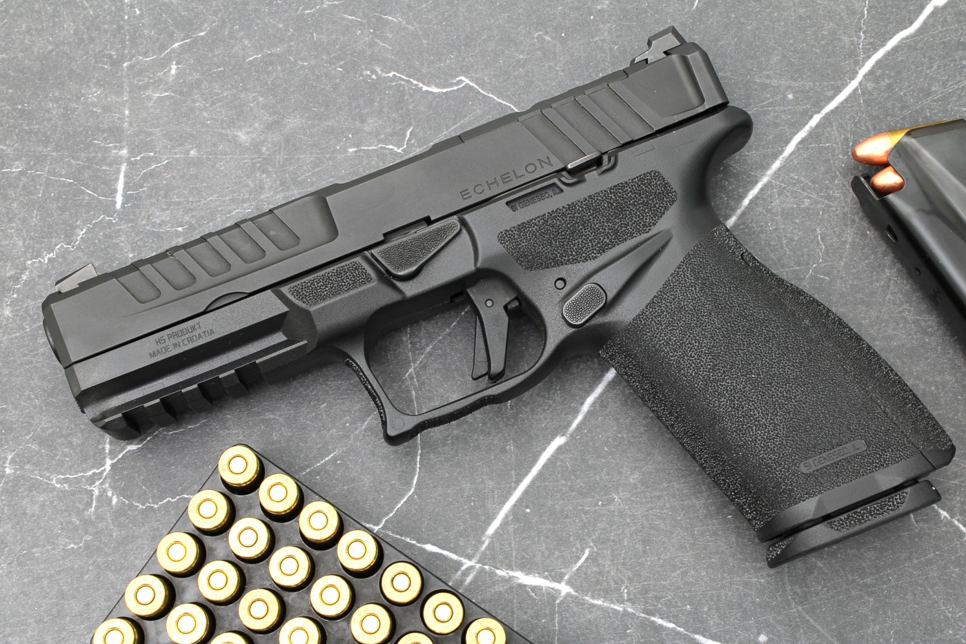 A right-profile product shot of the California-compliant Springfield Armory Echelon 9mm, with the barrel, slide top, and grip angle all visible in the frame. The photograph highlights the pistol’s ergonomics — rounded grip, modular backstrap area, and textured panels — elements that contribute to consistent recoil control and handling. The optics-ready slide and sighting plane are shown, suggesting compatibility with red dot sights common on modern duty pistols. The composition makes the controls and trigger geometry legible, useful for understanding trigger reach and reset. For accessibility, the image conveys the firearm’s overall size and silhouette, relevant to the Echelon 4.5F and 4.0C family distinctions. This photo is intended to represent California-compliant Echelon pistols in editorial and product contexts.