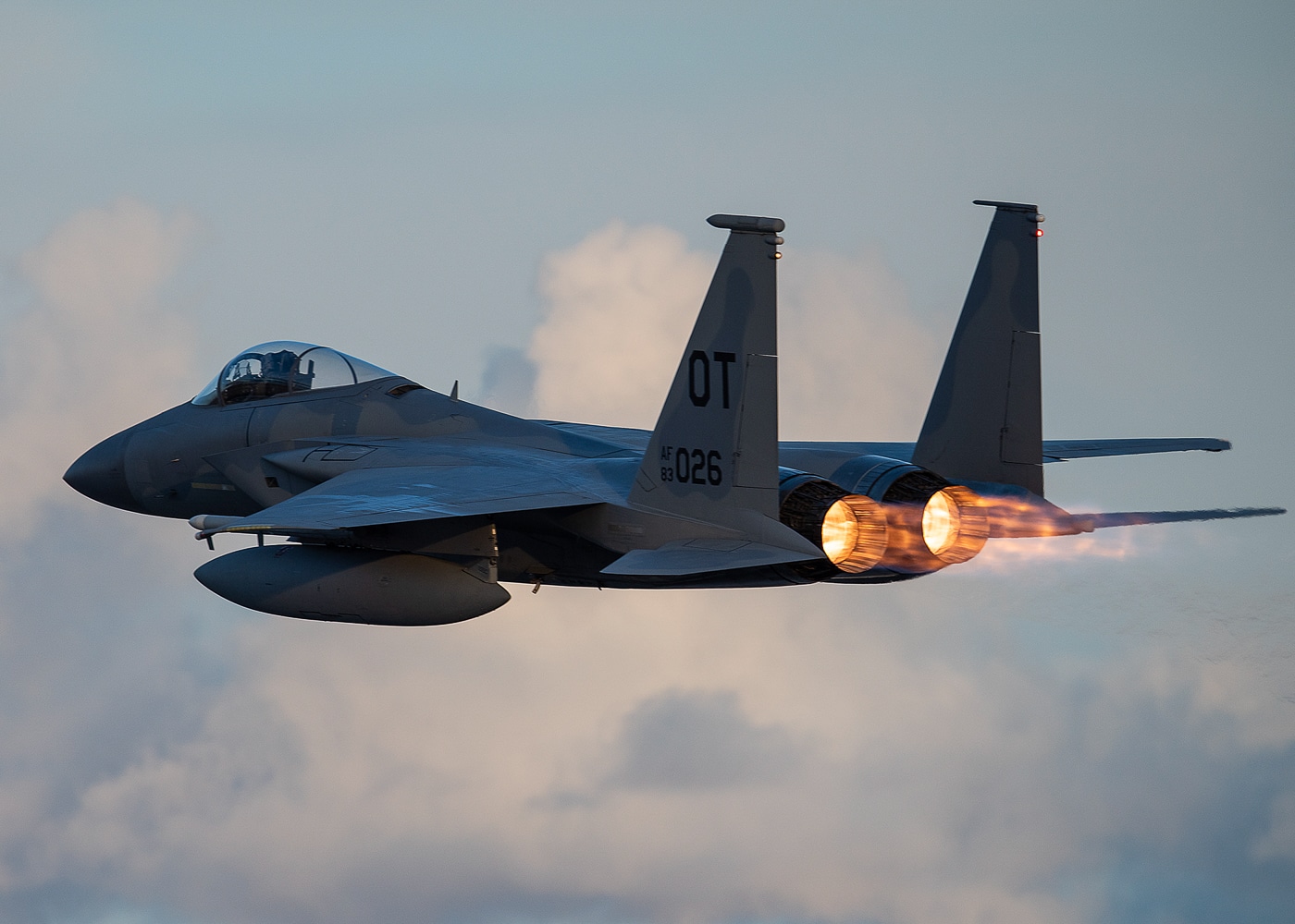 A U.S. Air Force F-15C Eagle fighter jet takes off from Nellis Air Force Base, Nevada, during a daytime training mission. The photo captures the aircraft moments after leaving the runway, with its landing gear still extended and afterburners glowing. The desert mountains and dry terrain surrounding Nellis are visible in the background. The F-15C, designed for air superiority missions, has been a key part of U.S. air combat training programs for decades. Nellis AFB hosts exercises such as Red Flag, where pilots from around the world test combat tactics in realistic scenarios. This image reflects both the heritage and ongoing role of the Eagle in advanced fighter training. It highlights the raw power and precision that define the McDonnell Douglas F-15 design.