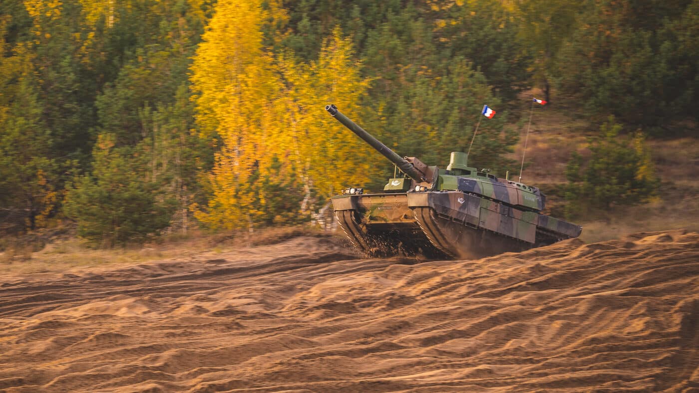 The photo shows a French Army Leclerc main battle tank participating in NATO’s Iron Spear exercise in Latvia. The tank is camouflaged and moving across open ground, with its 120mm main gun aimed forward. Iron Spear is a multinational event focused on live-fire competitions and armored readiness. The Leclerc represents France’s contribution to NATO’s enhanced forward presence in Eastern Europe. Its smaller size and autoloader system distinguish it from other NATO tanks in the exercise. The image emphasizes France’s commitment to alliance defense and interoperability with partner nations.