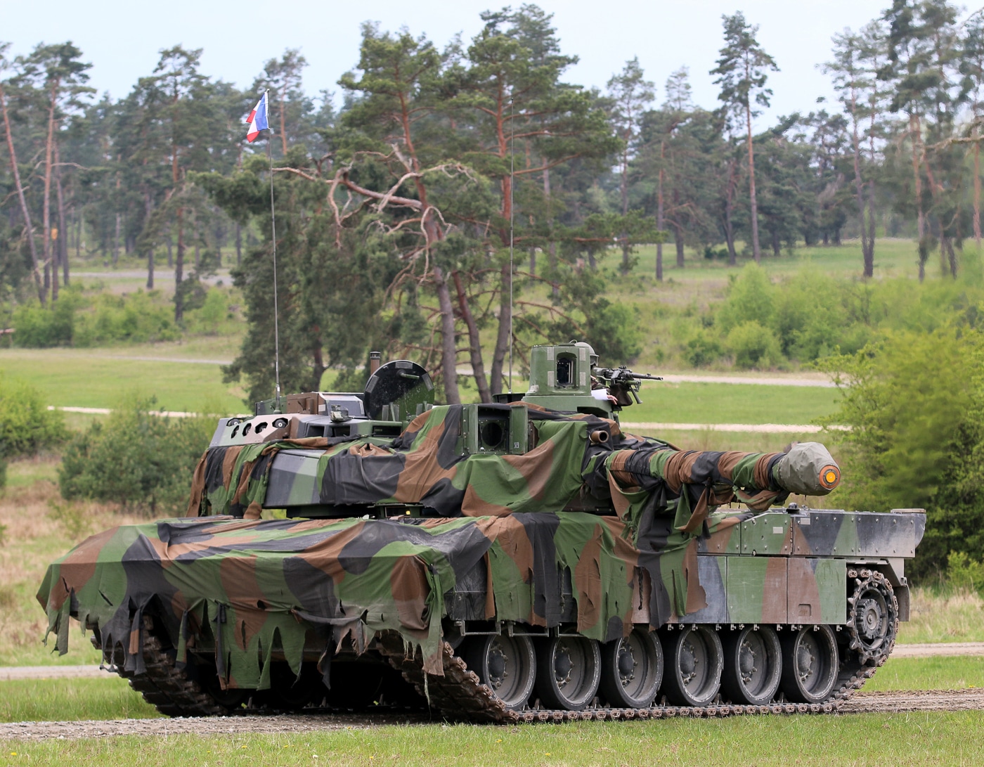 The photo shows a French soldier positioned on top of a Leclerc main battle tank, engaged in identifying friendly and enemy vehicles. The soldier is wearing combat gear and scanning the surrounding terrain, possibly using binoculars or visual observation. This exercise highlights the importance of vehicle recognition to prevent misidentification in fast-moving combat. The Leclerc provides a high vantage point and advanced optics to assist in target identification. Accurate recognition ensures effective communication between units and minimizes the risk of friendly fire. The image underscores the human role in battlefield awareness, complementing the tank’s technical systems.