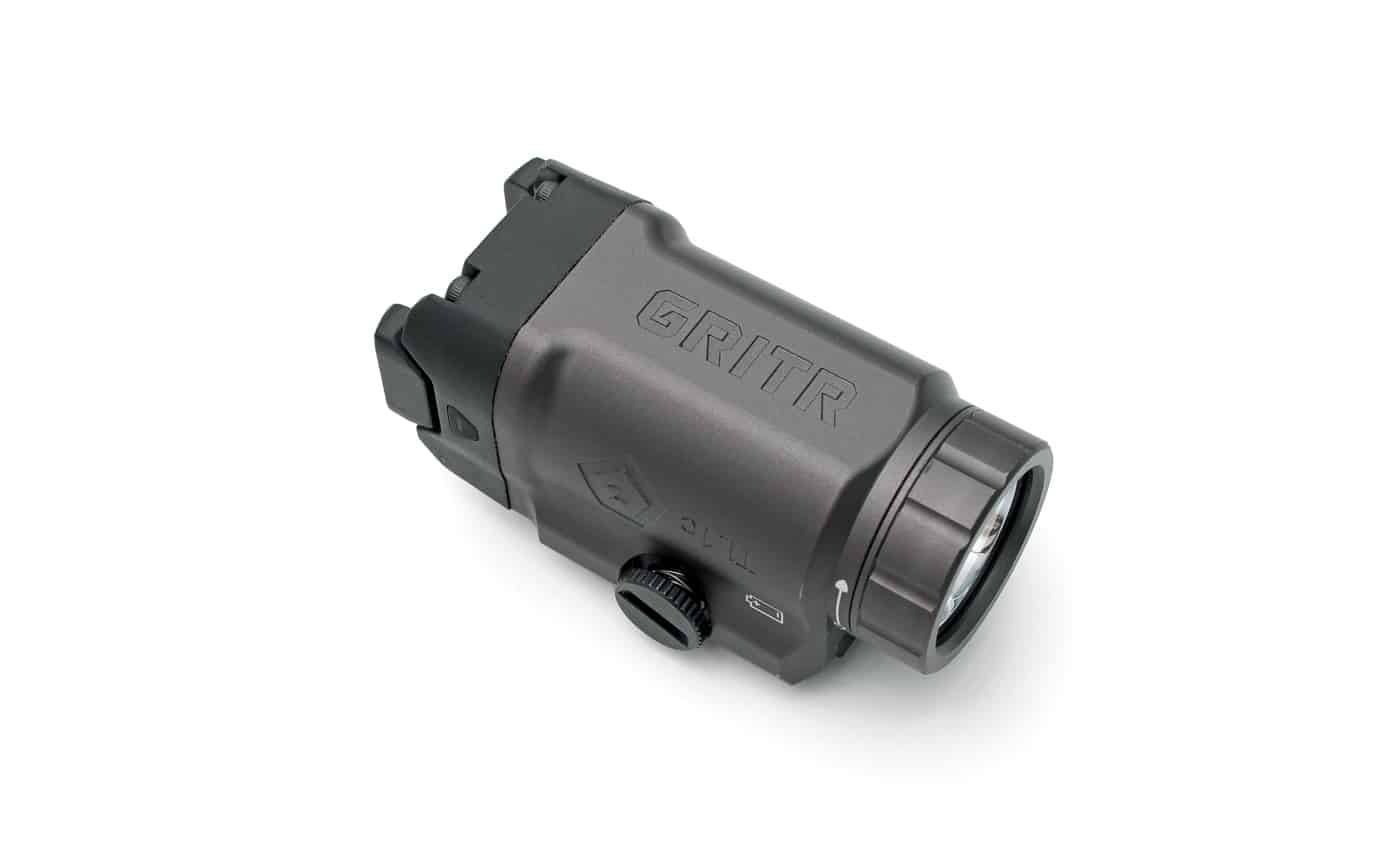 Close-up image of the GRITR TL1c Compact Weapon Light, focusing on its streamlined exterior and almost unbranded finish. The weapon light is shown mounted to a handgun rail, emphasizing its tight fit and tactical appearance. Unlike many competitors, the GRITR TL1c features very subtle embossing instead of bold logos or graphics, which helps the unit maintain a stealthy and professional look. The matte, tungsten gray anodized aluminum is visible, showing attention to detail in both color and finish. The photo supports the article’s discussion about understated design choices and the value of minimal branding for practical use. Related terms: concealed carry weapon light, low-profile tactical accessory, discreet pistol flashlight, GRITR TL1c review. The setup is clean, with the product in clear focus and nothing distracting from the subject.
