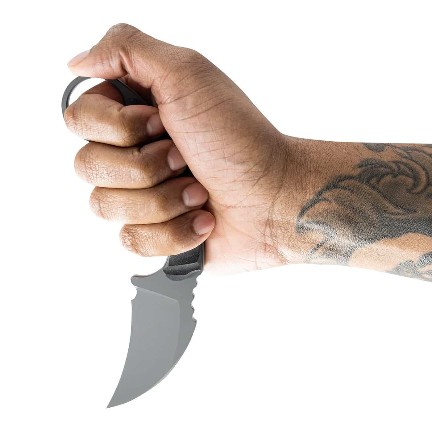 Photo of the Toor Knives Karsumba R being held in an icepick, or reverse, grip. The blade’s curved hawkbill shape angles downward, showing how the design aligns with close-quarters use. The retention ring sits around the user’s finger, ensuring the knife stays secure during rapid transitions. The Phantom Grey G10 handle and jimping on the spine are visible, illustrating control and stability in this grip position. The image supports the article’s discussion of martial ergonomics and grip versatility. It conveys how the Karsumba R’s design builds on traditional karambit function with modern materials.
