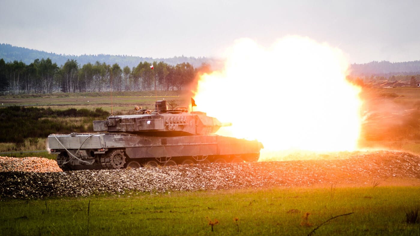 A French Leclerc main battle tank captured mid-fire as its 120mm smoothbore gun discharges during NATO training exercises at Grafenwöhr Training Area in Germany. A bright muzzle flash and dust cloud can be seen as the round leaves the barrel. The tank is camouflaged and positioned on open terrain, emphasizing its battlefield role. The Leclerc’s advanced autoloader system allows it to achieve a high rate of fire compared to other Western tanks. This training demonstrates the accuracy and effectiveness of the tank’s fire control systems. The image highlights France’s contribution to NATO interoperability and readiness.