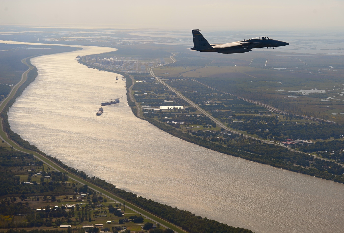 A Louisiana Air National Guard F-15D Eagle is photographed in flight over the Mississippi River. The two-seat fighter, painted in standard gray camouflage, is seen from an air-to-air perspective with the river’s winding channel below. The F-15D is a dual-control variant used for both combat missions and pilot training. Reflections from the water enhance the view of the aircraft’s silhouette as it maintains steady altitude. The image captures the contrast between advanced military aviation and the natural geography of the American South. The Louisiana Air National Guard regularly conducts sorties like this to maintain combat readiness and pilot proficiency. This photo underscores the Guard’s continued role in homeland defense and regional air superiority missions.