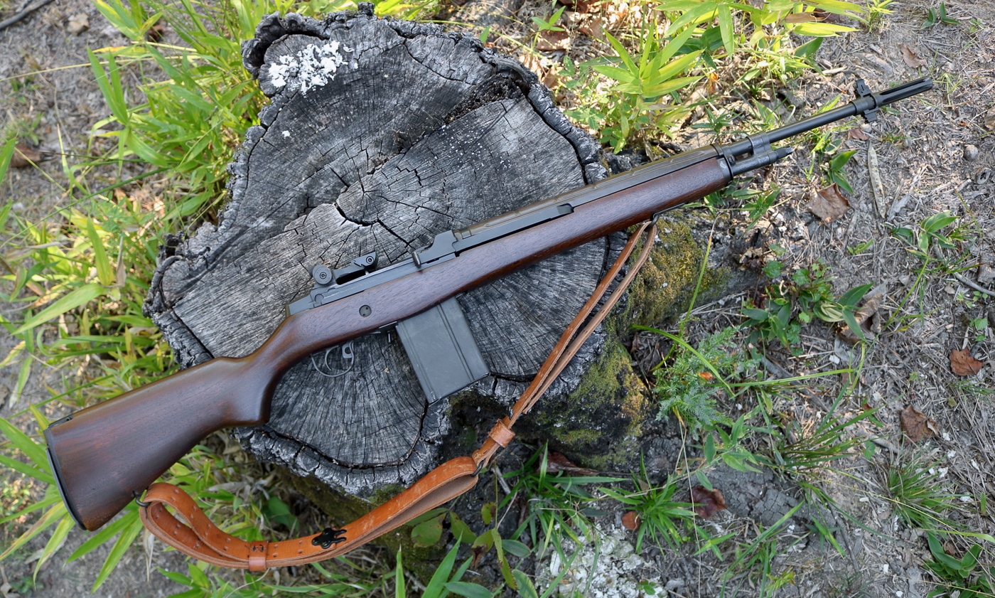 A Springfield Armory M1A rifle is pictured outdoors during a day of shooting. The rifle rests on a shooting mat or natural ground surface, surrounded by open terrain and sunlight. Its wood stock and steel receiver show the traditional craftsmanship that defines the M1A design. This setting highlights the rifle’s balance of durability and precision, suited for both range practice and field shooting. The image captures the simplicity and reliability of the platform, with the bolt, sights, and magazine clearly visible. The background suggests a calm shooting environment, emphasizing usability and comfort. The photo reinforces the M1A’s reputation as a dependable semi-auto rifle for recreational and sporting use.