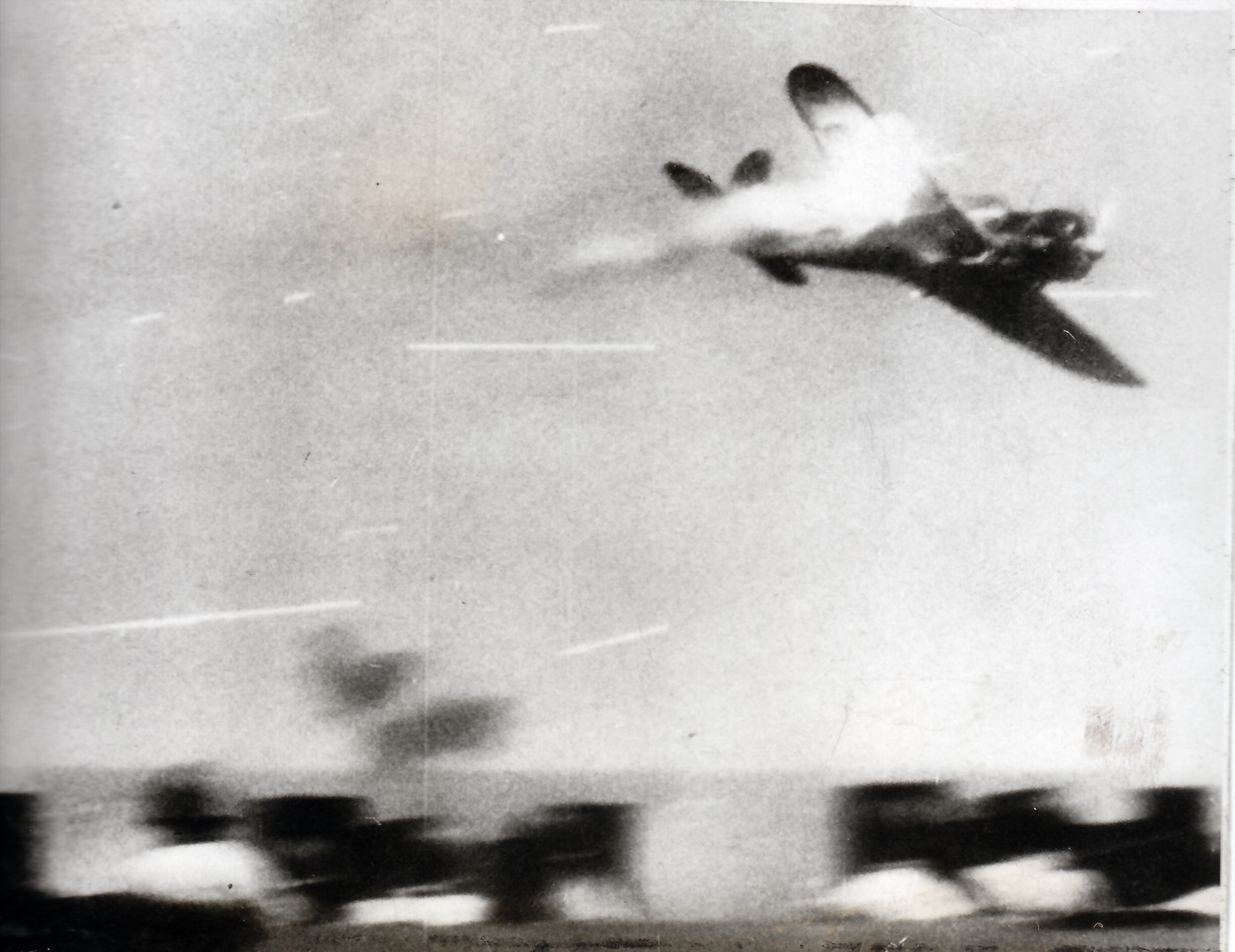 A dramatic wartime photo shows a Japanese Nakajima B5N “Kate” torpedo bomber descending toward a U.S. Navy aircraft carrier during a kamikaze attack. The plane appears to be in a shallow dive, its undercarriage retracted and a smoke trail behind one wing. Anti-aircraft bursts fill the sky as the ship’s guns open fire. The ocean below reflects sunlight, emphasizing the aircraft’s rapid descent toward the carrier deck. Once the mainstay of Japan’s early war torpedo squadrons, the B5N was later used in suicide missions when conventional attacks failed. This image captures the desperate tactics of Japanese Kamikazes in World War II and the intensity of late-war naval combat in the Pacific.
