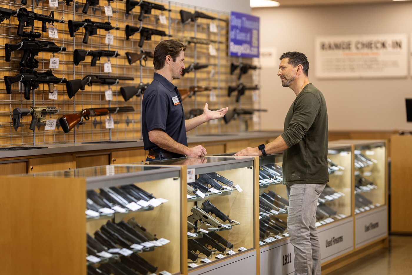 Photo of a neatly arranged display of rental firearms inside a Range USA facility. The image includes various handguns and rifles organized in secure racks, each labeled for easy identification. The guns appear clean and well-maintained, reflecting Range USA’s commitment to safety and equipment quality. Bright lighting and clear signage make the area approachable for new shooters. Staff members may be visible in the background assisting customers or explaining features. The image conveys the company’s mission to make firearm exploration accessible and responsible. It also represents Range USA’s focus on offering safe, consistent rental programs nationwide.