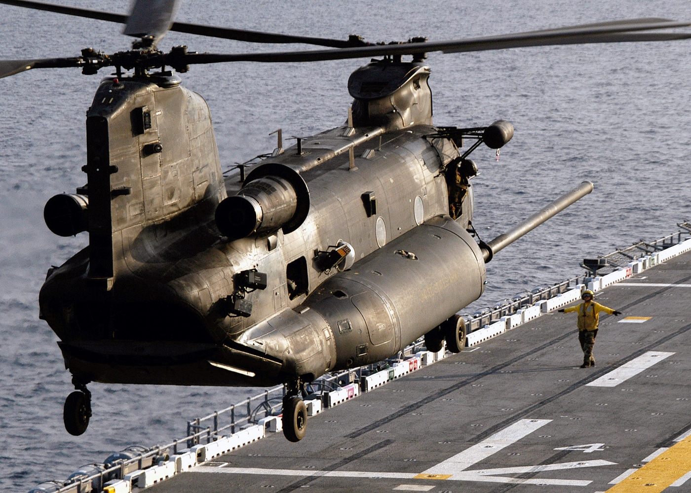 The image captures a US Army MH-47 Chinook helicopter, assigned to the 160th Special Operations Aviation Regiment (Airborne) at Fort Campbell, Kentucky, departing the flight deck of the US Navy amphibious assault ship USS WASP (LHD 1) during deck landing qualification training. The Chinook, with its tandem rotors spinning, lifts off from the ship’s marked landing area, with the vast expanse of the ocean visible in the background. Deck crew in colored vests and helmets may be seen on the flight deck, providing hand signals and ensuring safe operations. The USS WASP’s island superstructure, aircraft markings, and various naval equipment are visible, emphasizing the joint Army-Navy environment. The image highlights the importance of deck landing training for Army aviation units supporting maritime and amphibious missions. The photo demonstrates the technical skill required for precise shipboard operations, as well as the coordination between the 160th SOAR flight crew and Navy personnel. This type of training is vital for enabling rapid deployment and joint special operations at sea.