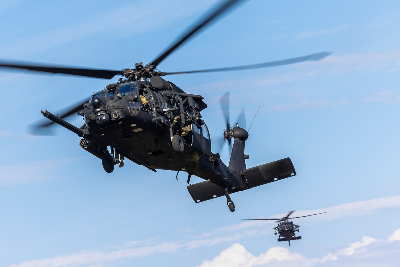 The image shows a formation of U.S. Army MH-60 Black Hawk helicopters assigned to the 160th Special Operations Aviation Regiment (Airborne) approaching Marine Corps Outlying Field Atlantic during a forward arming and refueling point (FARP) exercise on May 6, 2025. The helicopters are flying low in close formation, their rotors kicking up dust and debris as they near the landing zone. The scene includes the open expanse of MCOLF Atlantic, with visible training range markers, temporary fueling equipment, and possibly support vehicles or personnel on the ground. This FARP exercise involves rapidly landing, refueling, and rearming helicopters to sustain special operations missions in austere or contested environments. The Night Stalkers’ emphasis on speed, precision, and logistical coordination is evident in the photo. The event utilizes MCAS Cherry Point’s facilities, highlighting joint use of Marine Corps resources for Army aviation training. The image underscores the operational flexibility and expeditionary capability of the 160th SOAR.