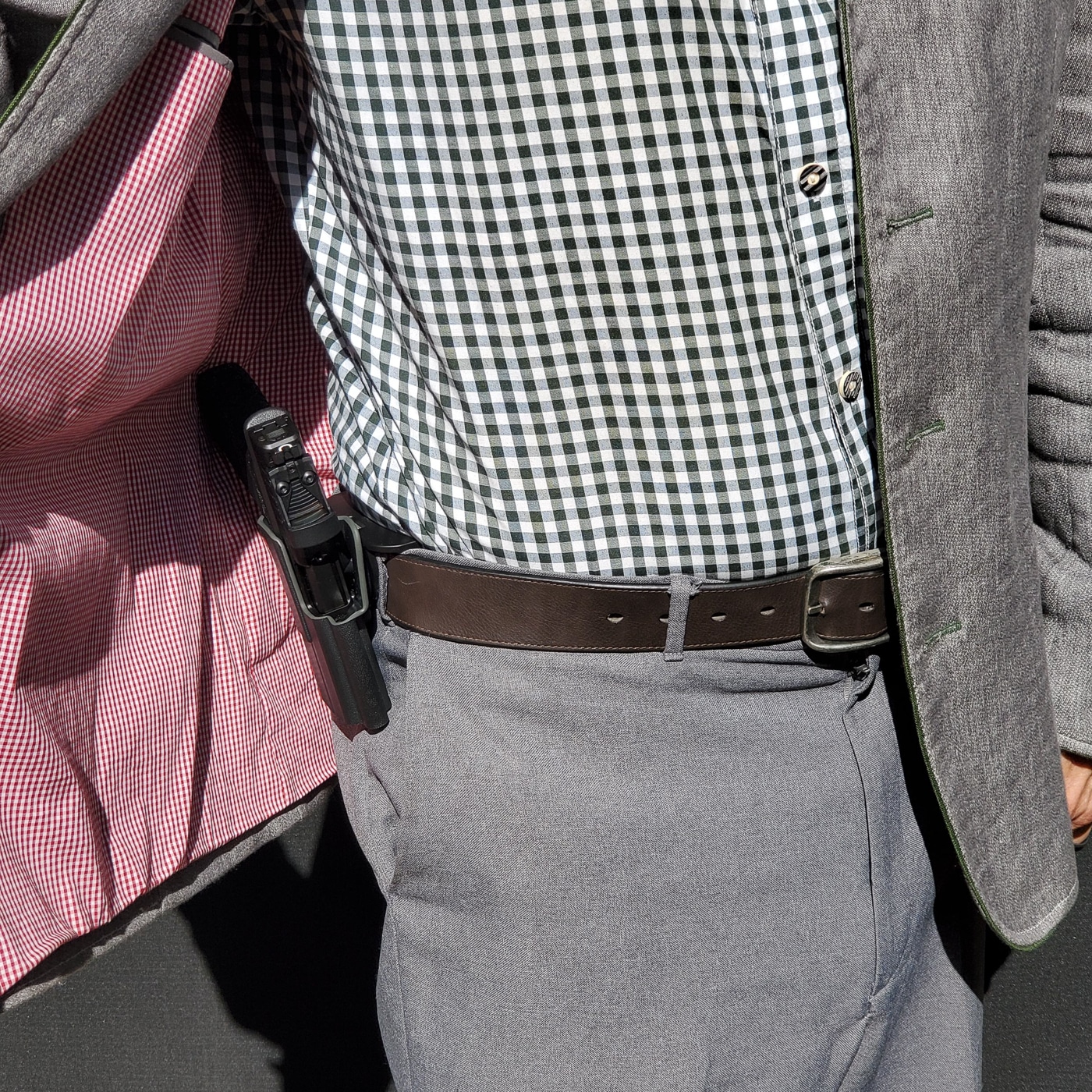 A person wearing a Springfield Armory pistol in a paddle holster with a jacket covering the firearm. The holster sits outside the waistband while the paddle secures inside the waistband against the hip. The jacket drapes over the pistol grip, reducing printing and allowing the firearm to remain concealed during normal movement. This example demonstrates how paddle holsters can be used for everyday carry with the right clothing choice. The position appears to be around the 3–4 o’clock area, commonly recommended for right-handed shooters. Paddle holsters like this offer the convenience of fast on-and-off use while still working in a concealed carry role under outer garments. Keywords: Springfield Armory, paddle holster concealment, jacket concealed carry, OWB holster, firearm carry setup.