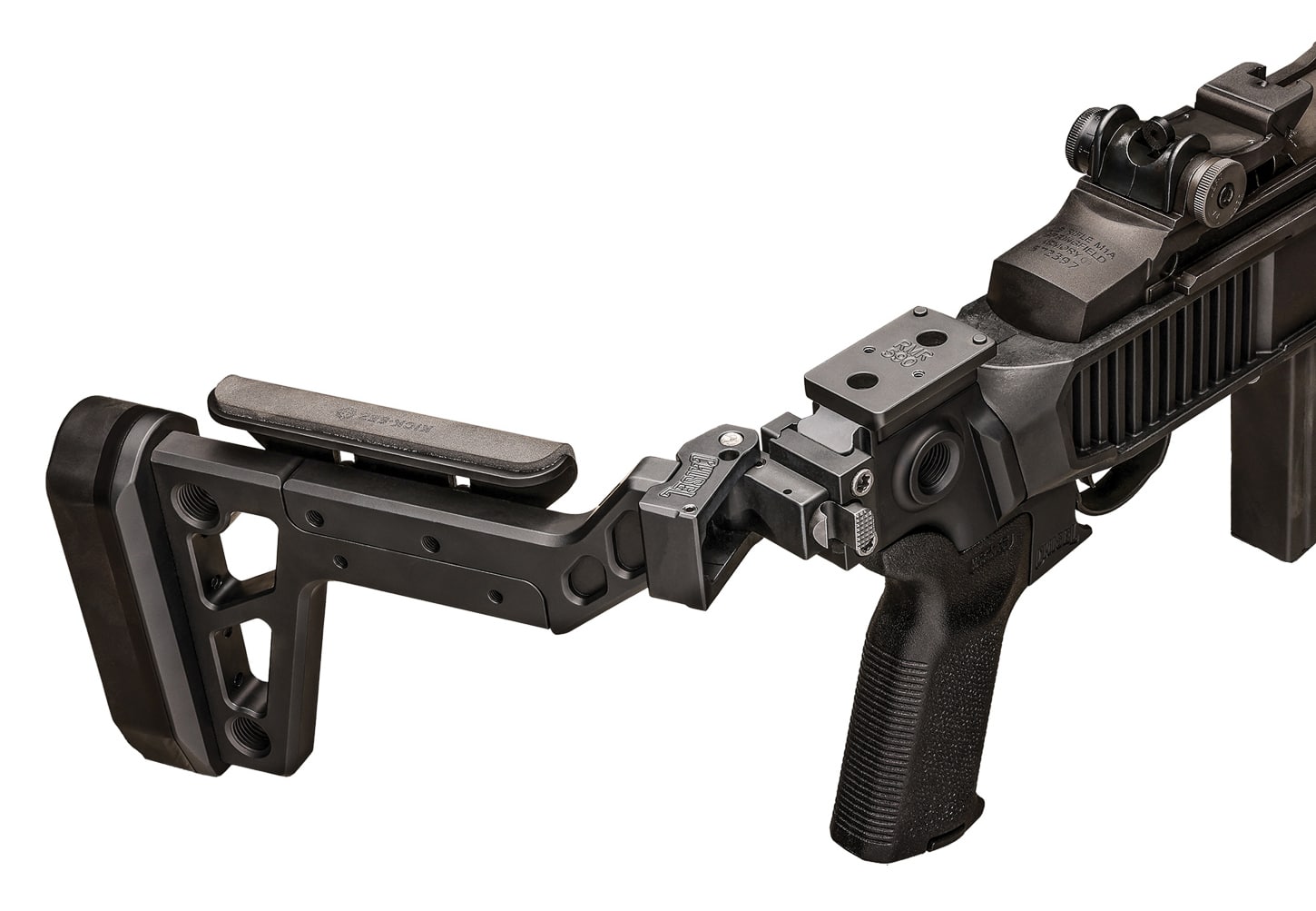 Detailed view of Chisel Machining aluminum billet side-folding assembly mounted to Delta 14 Chassis Gen 2 via Mossberg 500 pattern attachment system showing precision machined components and adjustment features. The aluminum construction provides exceptional rigidity when locked in deployed position for shooting the M1A SOCOM rifle. Height-adjustable KICK-EEZ cheekrest allows customization for proper optic alignment and consistent cheekweld with various sight configurations. KICK-EEZ recoil pad at rear mitigates felt recoil from powerful 7.62 NATO cartridge during extended shooting sessions. Multiple sling mounting points visible throughout assembly provide tactical carry flexibility for different shooting positions. AR-pattern Magpul MOE-K2 pistol grip offers ergonomic hand positioning and familiar controls for shooters transitioning from AR-15 platforms. Side-folding mechanism dramatically reduces rifle overall length for vehicle storage and confined space deployment. The premium buttstock elevates the base Delta 14 chassis to complete tactical package priced at $579.99 as-tested.