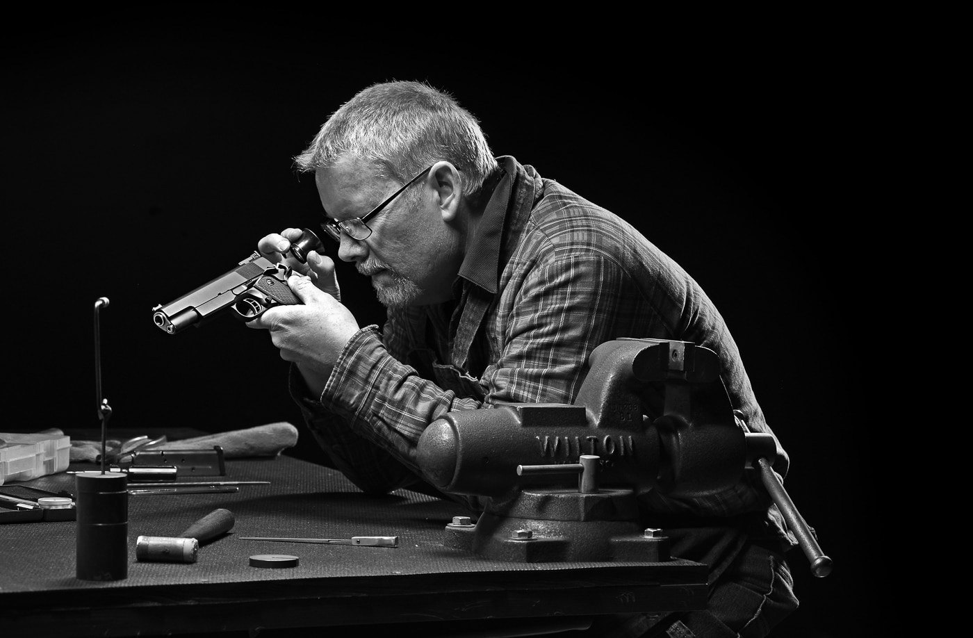 Professional gunsmith inspecting a 1911 pistol in his workshop where custom modifications transform basic models into expensive enhanced variants. Skilled craftsmen offer trigger jobs, beveled magazine wells, extended safeties, and optical sight cuts that significantly increase final costs. Plain jane 1911 models provide adequate defensive reliability without custom shop work that can add thousands to base prices. The Springfield Armory Mil-Spec at $725 delivers century-proven performance compared to $3,000+ for fully customized guns. Standard configuration pistols served military personnel and law enforcement effectively throughout history without gunsmith enhancements. Custom work might be fun and look impressive, but basic models feed hollow points reliably when properly throated from the factory. Budget-conscious shooters can purchase multiple standard 1911 pistols for the cost of one tricked-out custom build.