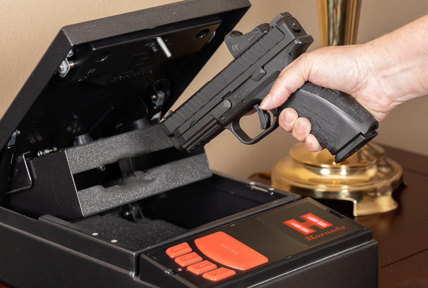 Homeowner accessing Springfield XD Mod 3 pistol from safe for self defense scenario demonstrating practical defensive firearm preparation. The handgun likely contains quality defensive ammunition at an appropriate bullet weight tested for reliable feeding and terminal performance. Selecting bullet weight for self defense involves understanding how grain weight affects penetration and expansion in your specific carry gun. Quick access to defensive firearms matters more than theoretical optimization of bullet weight when facing immediate threats requiring armed response. Springfield XD pistols function reliably with various bullet weights when shooters select quality defensive ammunition from reputable manufacturers. Home defense scenarios typically occur at close distances where bullet weight differences have minimal practical impact on terminal ballistics. Training with your defensive handgun and chosen ammunition grain weight ensures familiarity with recoil characteristics and point of impact under stress. Proper self defense preparation includes selecting appropriate bullet weight, testing defensive loads thoroughly, and practicing shot placement with your specific carry gun.
