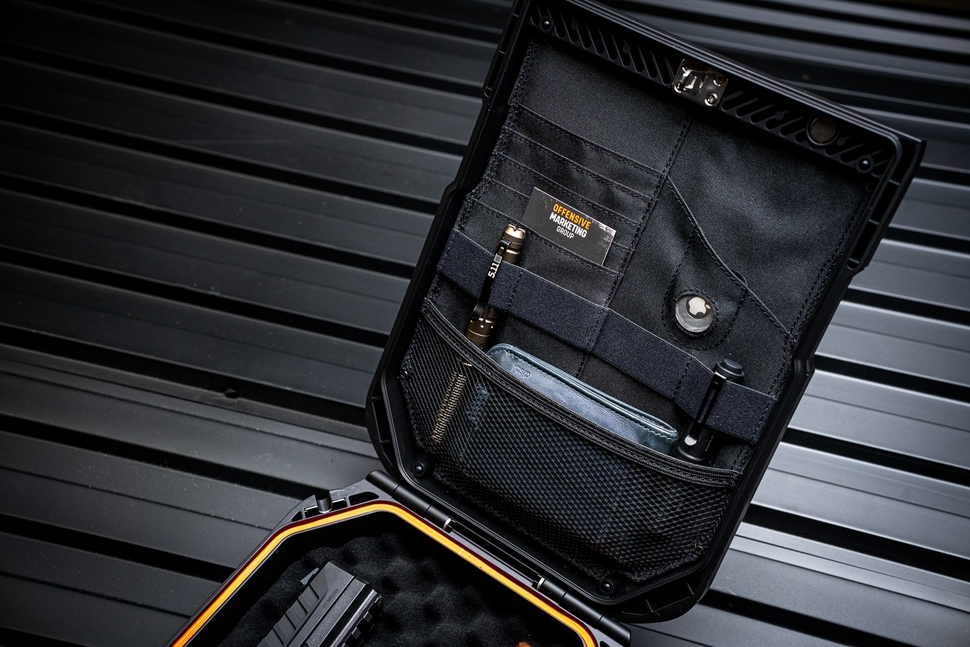 Interior view of the Vaultek Lifepod 20 Biometric showing the lid organizer in use. Several mesh and fabric pockets are built into the inside of the lid, holding everyday carry items such as cards, a key, folded papers, and an Apple AirTag for tracking. The AirTag pocket is placed for easy access but remains secure during travel. This feature highlights how the safe can store not only firearms but also small valuables and important personal items. The organizer system keeps everything in place while the case is shut and latched, preventing items from shifting around. The design adds practical storage management to a portable firearm and valuables case, making it appealing to travelers, EDC enthusiasts, and anyone needing compact organization.