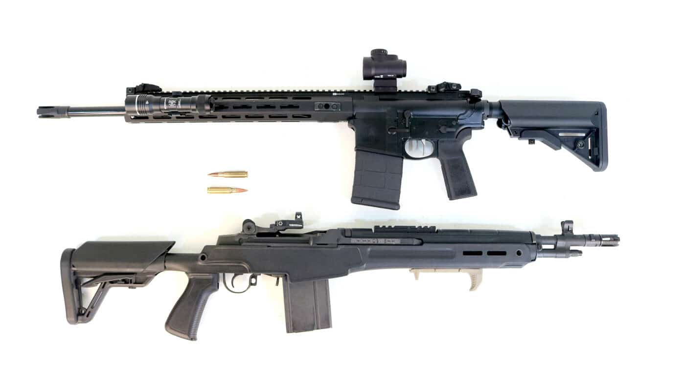 A modern Springfield Armory M1A and AR-10 rifle are shown side by side for comparison. The M1A features a walnut or composite stock with a traditional rifle profile, while the AR-10 has a tactical, modular appearance with aluminum and polymer components. This photo illustrates how both rifles, though chambered in .308, take entirely different design paths. The image highlights the contrast between wood and metal finishes, traditional craftsmanship and contemporary engineering. Lighting is neutral, emphasizing form and detail equally. The rifles are positioned evenly to invite comparison without bias. The scene captures the core of the article’s theme — old-school reliability versus modern adaptability.