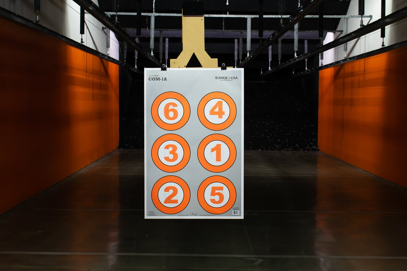Interior photo of a new Range USA indoor shooting lane showing a paper target suspended at the far end. The lane is brightly lit and lined with acoustic materials for noise reduction. The shooting booth is clean, organized, and features sturdy barriers for safety between shooters. The target shows several visible bullet holes from recent practice. The environment reflects Range USA’s focus on professionalism, safety, and an inviting space for both new and experienced marksmen. Overhead lighting and clear sight lines emphasize the company’s commitment to well-designed, user-friendly ranges.