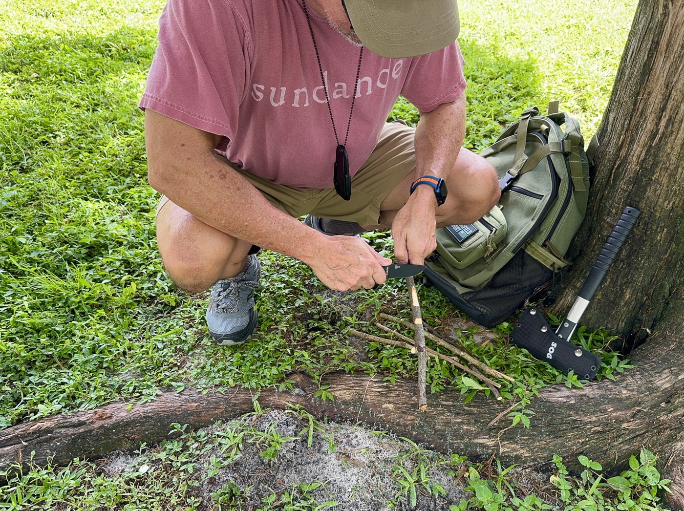 A small fixed-blade neck knife in a molded polymer sheath is displayed with outdoor gear such as a coiled rope, a backpack, and a water bottle. The knife hangs on a breakaway chain, showing its intended use for quick access during hiking or paddling. Its compact size makes it easy to carry without adding bulk to a minimalist kit. The photo emphasizes how neck knives are useful for cutting cordage, opening packages, or preparing camp materials. The placement of the knife among trail gear suggests it is a practical choice for both safety and utility. This description helps visually impaired users understand how neck knives function in an outdoor environment while optimizing for keywords like neck knife, outdoor knife, camping gear, and utility blade.