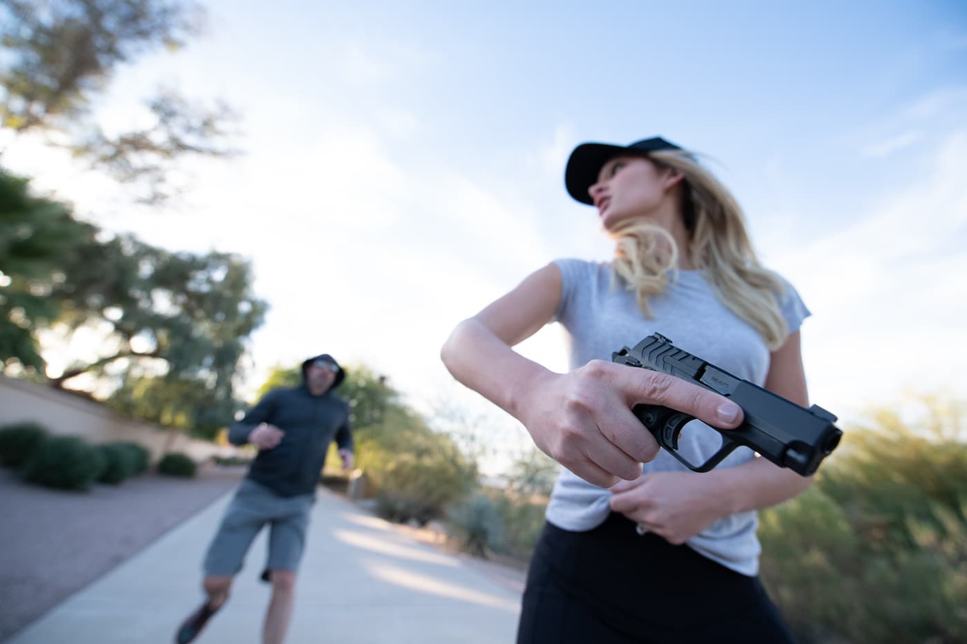 This photo shows a woman drawing a handgun from a concealed holster at their waist, intended to convey preparedness in self-defense situations. The setting is non-specific, keeping the focus on the action and the larger topic of how to survive a gunfight. The image relates directly to the skills and mindset needed to act under pressure and manage threats safely. Emphasis is placed on competence and regular training, as recommended in articles about personal protection and survival tactics. Details like the grip and draw technique highlight the importance of safe firearm handling. The neutral background and practical clothing reinforce a realistic, responsible approach to concealed carry. The photo is designed to accompany educational content on surviving violent confrontations and building mental resilience.