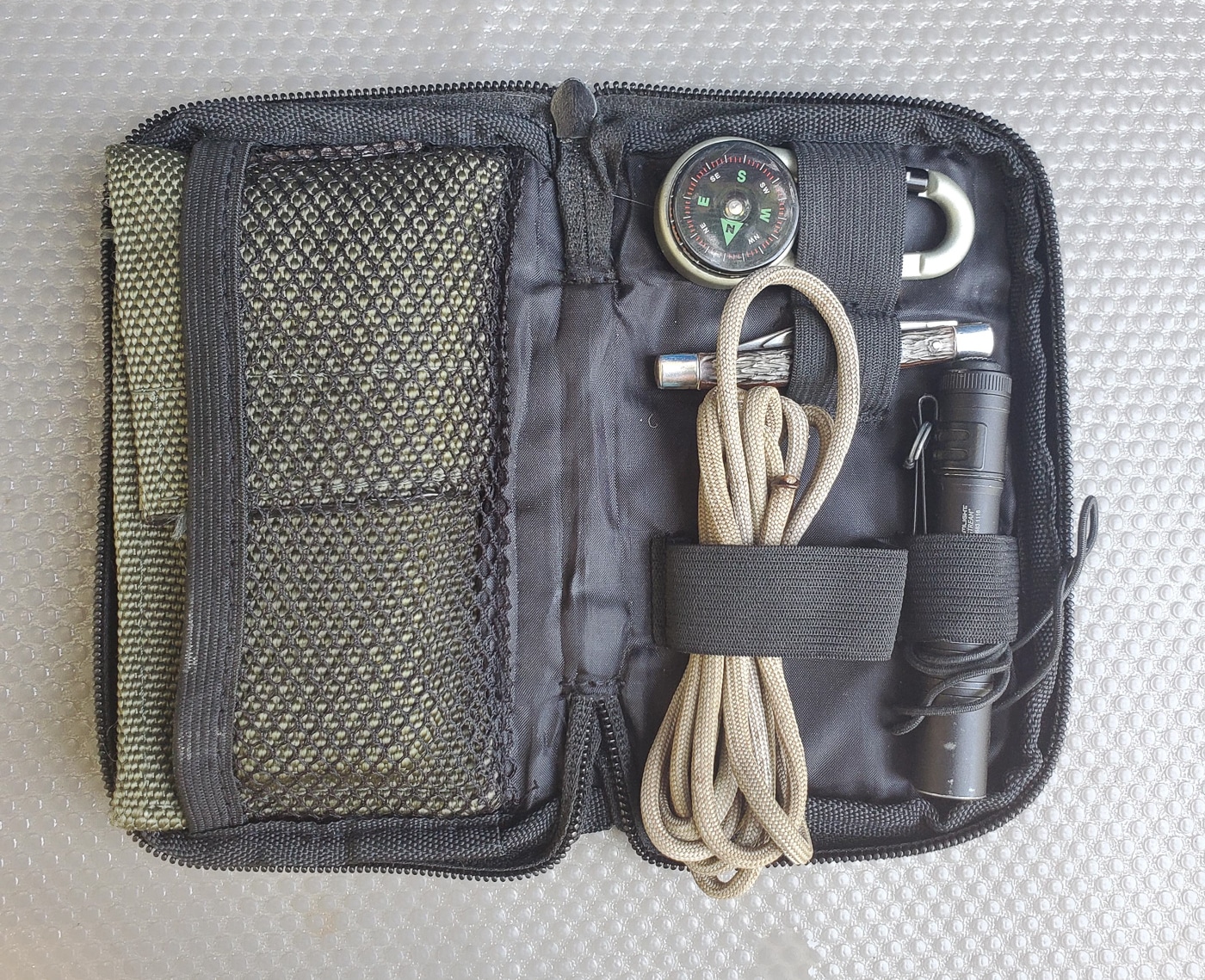 Compact everyday carry kit showing basic EDC essentials for personal protection and self-defense readiness without unnecessary bulk or excess gear. The streamlined setup includes core items like a quality knife for cutting tasks, a reliable flashlight for illumination needs, and other fundamental tools that form the foundation of practical preparedness. This minimalist approach to everyday carry reflects the article's advice to start small and avoid buying every tactical gadget available. The portable size allows for easy carry in cargo pants pockets, a belt pouch, or small fanny pack without drawing attention or creating discomfort during daily activities. Building an EDC kit around basic self-protection tools ensures you have essential gear accessible when situations require immediate response.