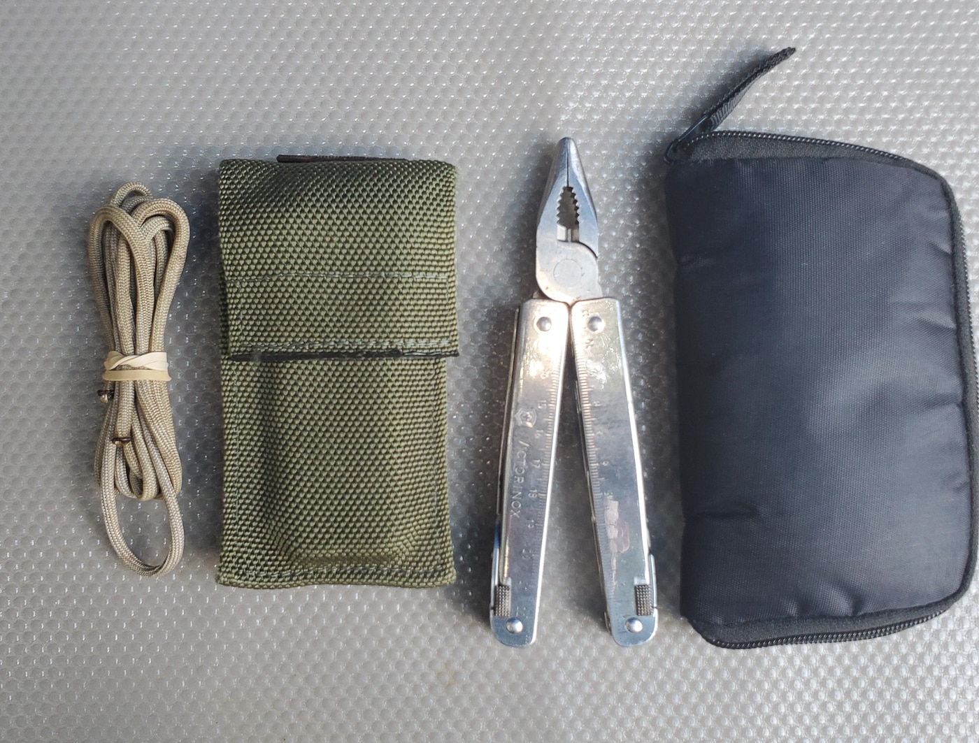EDC pouch containing paracord and a Leatherman multi-tool as part of a practical everyday carry self-protection and preparedness setup. The organizational pouch keeps these versatile tools accessible and prevents them from getting lost among other gear in a backpack or vehicle bag. Paracord serves countless emergency uses including securing equipment, building improvised shelters, creating tourniquets in medical emergencies, and dozens of other survival applications. The Leatherman multi-tool combines pliers, knife blades, screwdrivers, and other implements into one compact package that handles repairs, cutting tasks, and general problem-solving in the field. Including organized pouches in your EDC loadout ensures quick access to critical gear when situational awareness indicates a developing threat or emergency situation requiring immediate response.