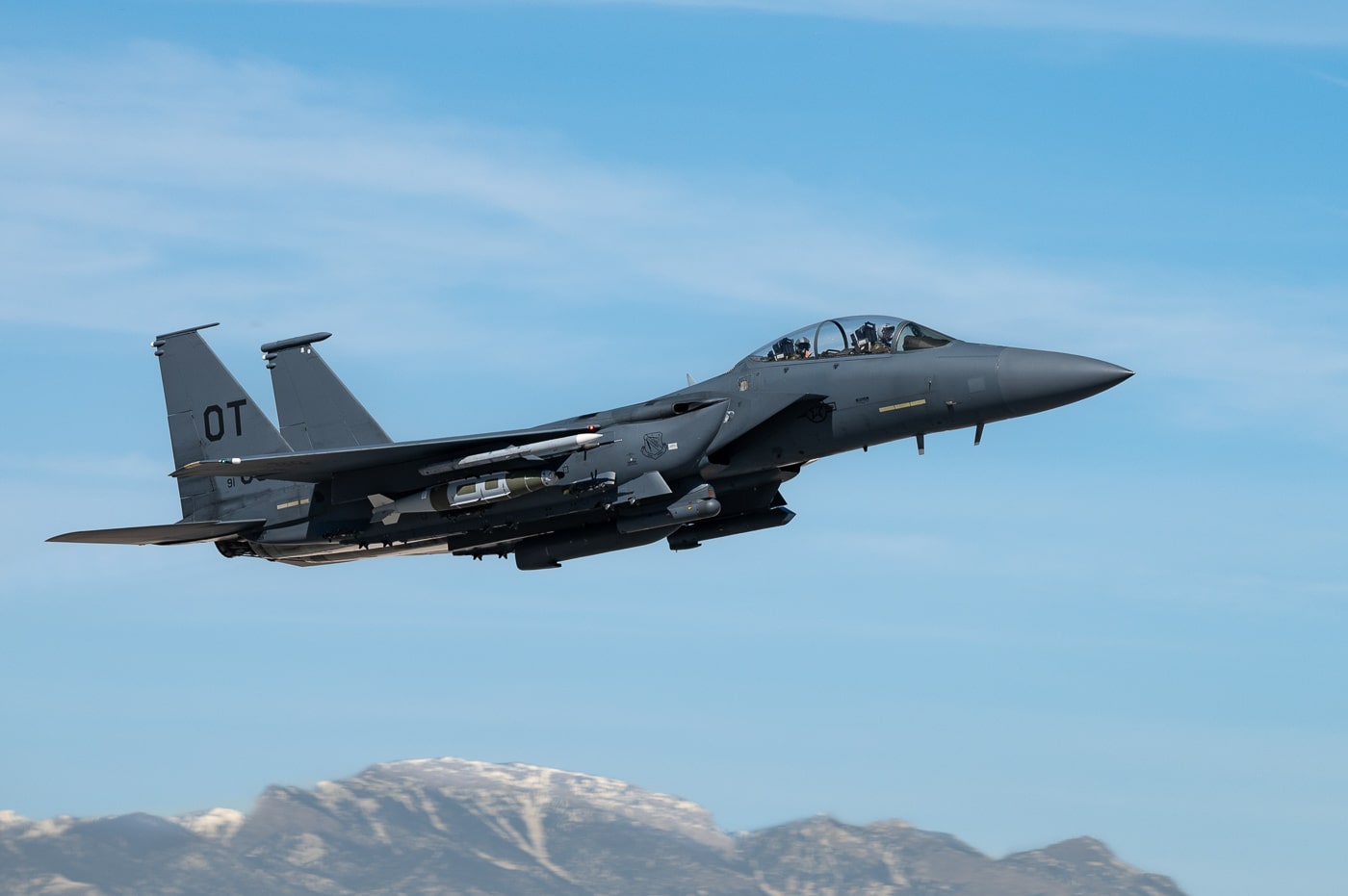 F-15E Strike Eagle tactical fighter assigned to 422nd Test and Evaluation Squadron launching from runway at Nellis Air Force Base Nevada during weapons testing mission in April 2023. The twin-engine multirole combat aircraft features landing gear retracting after takeoff with afterburners engaged on Pratt Whitney F100 turbofan engines. The 422nd TES performs developmental testing of GBU-56C laser-guided GPS munition weighing 2,000 pounds for precision ground attack missions. Strike Eagle test aircraft carry advanced weapons including GBU-31 GPS-guided bombs, GBU-12 laser-guided bombs, and APKWS II advanced precision kill weapon system rockets. Nellis AFB located in Nevada provides test range facilities for evaluating F-15E avionics upgrades, EPAWSS electronic warfare systems, and Sniper XR targeting pods. The United States Air Force relies on test squadrons to validate new weapons delivery capabilities before operational deployment with tactical fighter wings at Seymour Johnson Air Force Base and Royal Air Force Lakenheath England.