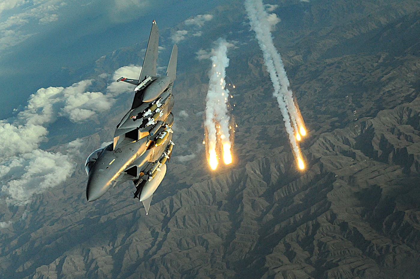 McDonnell Douglas F-15E Strike Eagle tactical fighter deploying infrared countermeasure flares over Afghanistan during Operation Enduring Freedom combat operations in 2008. The twin-engine multirole combat aircraft releases defensive flares from dispensers mounted on fuselage protecting Strike Eagle from heat-seeking surface-to-air missiles and man-portable air defense systems. F-15E Strike Eagles conducted extensive combat operations over Afghanistan providing close air support for coalition ground forces, precision strikes against Taliban positions, and aerial reconnaissance missions. The all-weather tactical fighter features defensive countermeasures including chaff dispensers for radar-guided threats and flare systems for infrared missile defense. United States Air Force deployed Strike Eagles to Bagram Airfield and other forward operating bases supporting Operation Enduring Freedom and Global War on Terror missions. The F-15E platform employed precision-guided munitions including GBU-12 laser-guided bombs and GBU-31 GPS-guided weapons against enemy command centers, weapons caches, and improvised explosive device factories. Strike Eagle crews coordinated with joint terminal attack controllers on ground providing close air support protecting U.S. Army, Marine Corps, and coalition forces engaged with enemy fighters.
