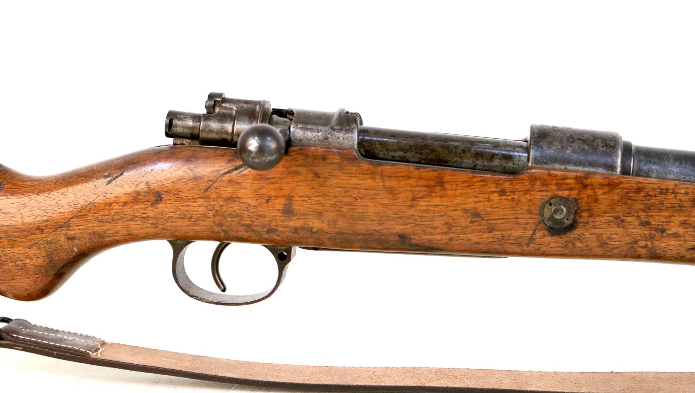 Close-up photograph of Gewehr 98 bolt action mechanism showing robust Mauser controlled-feed design that made the G98 rifle exceptionally tough and reliable under harsh World War I combat conditions in trenches across Europe. The Gew 98 bolt features dual locking lugs that engage steel receiver recesses providing positive lockup for firing 7.92x57mm Mauser cartridges plus third safety lug at rear of bolt assembly for additional strength. This German military rifle action includes gas relief holes on bottom of bolt directing hot gases away from shooter during case or primer failures, cam-assisted extraction for removing dirty or sticky spent cartridges, and three-position flag-style safety on bolt rear. The controlled-feed Mauser action visible here where extractor snaps over cartridge rim during feeding ensured reliable function even in muddy trench warfare conditions that German soldiers like Adolf Hitler experienced during Great War service with 16th Bavarian Reserve Infantry Regiment and other Imperial German units from 1914-1918.