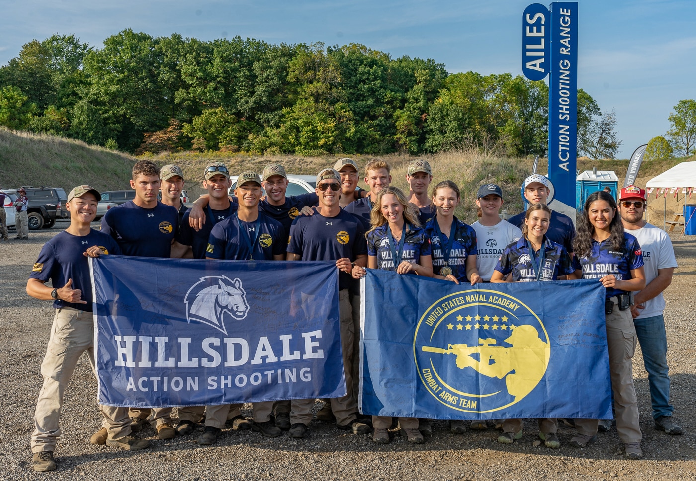 Members of the Hillsdale Chargers shooting team stand together with United States Naval Academy competitors at the 2025 USPSA Collegiate Action Pistol Championships held at the John A. Halter Shooting Center in Michigan. The Hillsdale College competitive shooting athletes and Naval Academy midshipmen represent two programs that both finished second in their respective team divisions at the Roger Ailes Action Pistol Shooting Center. Hillsdale action pistol team shooters and Naval Academy competitors demonstrate the camaraderie and sportsmanship that characterized the match where 13 university teams competed. The Hillsdale Chargers pistol program athletes joined with midshipmen who overcame significant challenges after match rule changes prohibited their issued pistols requiring Springfield Armory to provide Echelon 4.5F 9mm handguns. Hillsdale College shooting team members and Naval Academy shooters including Sam Reece, Michael Fulton, Noah Mayer, and Jack Newcomb who scored 2,662.2153 team points to win Limited division honors. The Hillsdale competitive shooting athletes and uniformed Naval Academy team members represent programs that exemplify finest sportsmanship regardless of school affiliation in collegiate USPSA competition. Hillsdale Chargers action pistol shooters and Naval Academy competitors both benefited from the premier facility and match organization provided by coaches Adam Burlew and Zechariah Steiger. The gathering of Hillsdale marksmanship team athletes with Naval Academy midshipmen illustrates the collegiate spirit and mutual respect among university shooting programs competing at this Michigan championship.