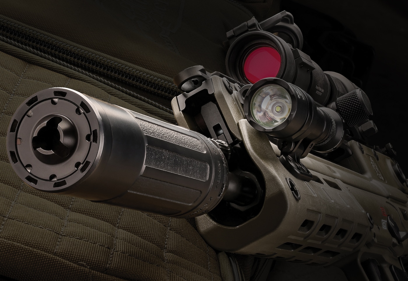 Complete defensive rifle configuration featuring Dead Air Sandman X centerfire rifle suppressor integrated with modern tactical accessories including optics, weapon lights, slings, and backup iron sights for real-world applications. The .30-caliber sound suppressor adds only 14.5 to 16.8 ounces of weight depending on KeyMo or Xeno mounting system while providing 6.4 to 6.9 inches of additional length that remains manageable for close-quarters defensive scenarios. Dead Air's Triskelion Gas Management System proves particularly valuable in defensive rifle setups by channeling combustion gases forward rather than venting back toward the shooter's face, preventing the asphyxiating experience common when firing suppressed rifles in enclosed spaces like home defense situations. The Sandman X's Haynes 282 superalloy construction maintains reliability under rapid-fire defensive shooting conditions where full-auto rated durability becomes critical rather than theoretical. Modern defensive rifle platforms benefit from reduced acoustic signature that preserves hearing during critical incidents while the suppressor's built-in flash suppressor front cap minimizes muzzle flash that degrades night vision. The compact rifle suppressor doesn't interfere with weapon-mounted lights, laser aiming devices, or forward grips commonly found on defensive carbine configurations. Tool-free suppressor mounting via Dead Air flash suppressor systems allows shooters to maintain multiple host firearms with quick-change capability.