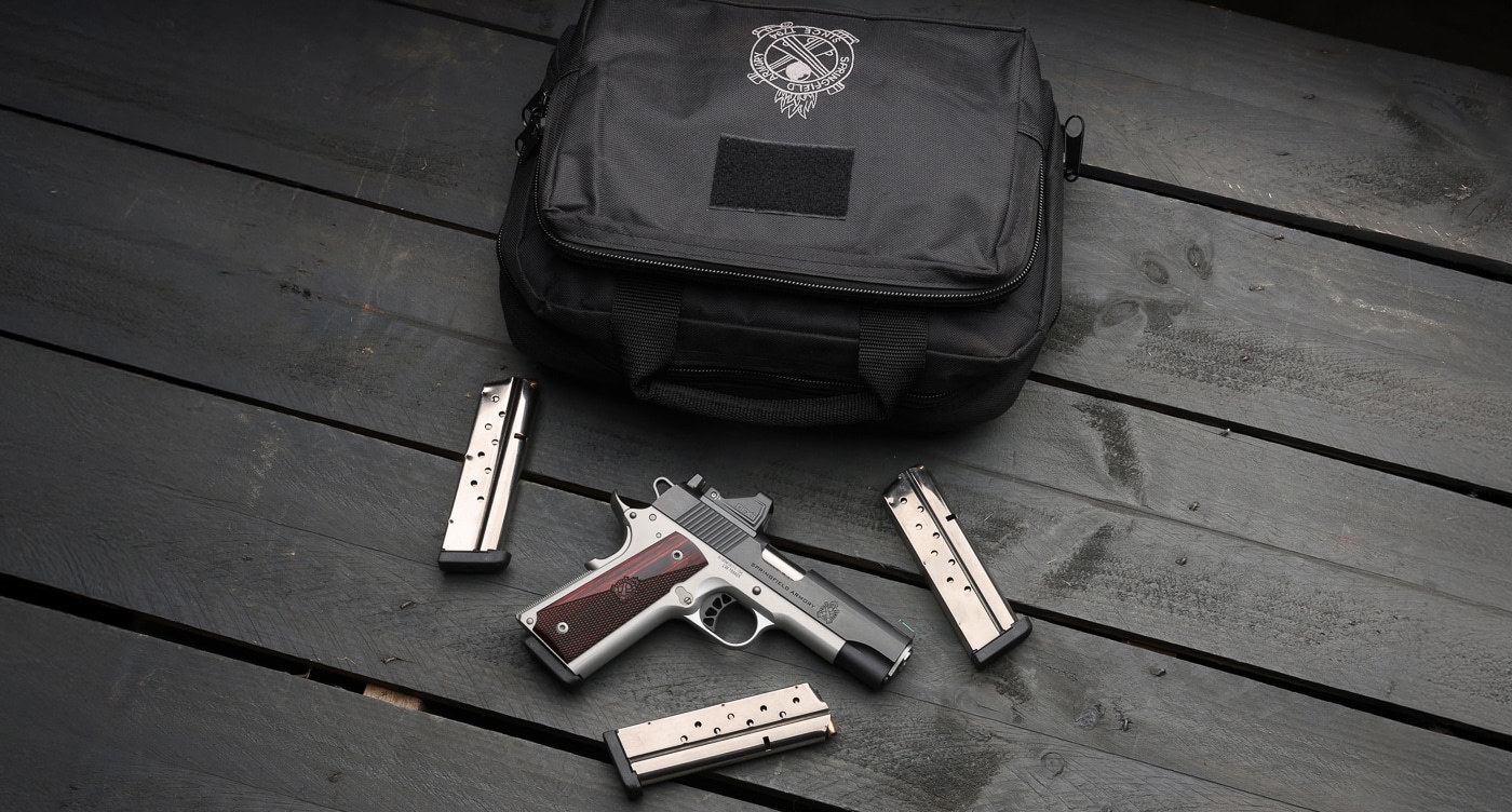 Springfield Armory 1911 Ronin Gear Pac bundle showing classic single-action pistol with factory-installed Viridian RFX11 green dot reflex sight and four magazines. The Ronin 1911 Gear Pac configuration combines Springfield's traditional 1911 platform with modern optic-ready capability, AOS A12B mounting plate, pre-installed reflex sight, and protective carrying case. Springfield 1911 pistol with Gear Pac accessories delivers classic single-action design upgraded with contemporary green dot sight offering 3 MOA reticle and Instant-On technology. Factory-equipped Ronin 1911 includes four magazines providing ammunition capacity for range training, defensive applications, and reload practice drills with traditional 45 ACP or 9mm chambering. Gear Pac Ronin configuration features AOS mounting system allowing secure optic installation while maintaining co-witness capability with iron sights through RFX11 reflex sight window. Springfield traditional 1911 platform with factory-mounted green dot eliminates post-purchase optic installation and sight-in procedures delivering ready-to-shoot classic pistol. Ronin 1911 Gear Pac bundle includes slide cover plate with integral rear sight allowing shooters to remove optic and run traditional iron sight configuration. Springfield classic pistol with complete accessory package represents permanent catalog offering worth up to $375 in complementary goods included with firearm purchase.