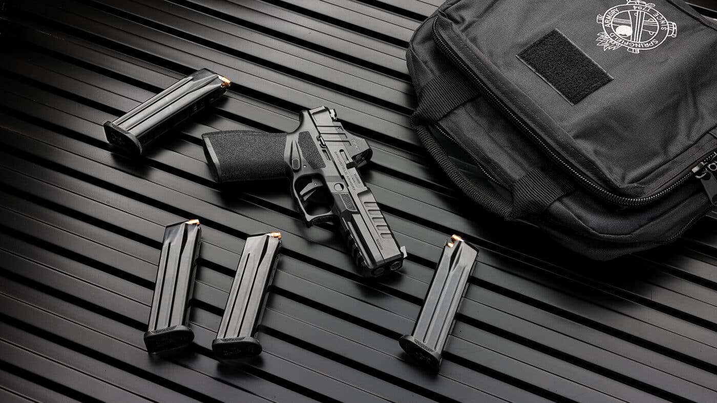 Springfield Armory Echelon pistol displayed with complete Gear Pac accessory kit showing Viridian RFX11 green dot reflex sight, four factory magazines, and protective carrying case laid out separately. The Echelon Gear Pac bundle demonstrates complete accessory package worth up to $375 included with Springfield's modular striker-fired platform as permanent catalog offering. Springfield Echelon pistol with Gear Pac accessories shows factory-installed optic with matching slide serrations, high-quality magazine complement for training and defensive use, and durable gun case with lockable zipper system. Complete Gear Pac kit for Echelon includes pre-mounted RFX11 reflex sight offering 3 MOA green dot reticle with Instant-On technology eliminating post-purchase optic installation requirements. Four magazines displayed with Echelon Gear Pac provide ammunition capacity for extended range sessions, reload practice drills, and maintaining separate carry versus training magazine rotation. Springfield modular platform accessory bundle shows complementary goods typically purchased separately with new firearm consolidated into single ready-to-shoot package. Echelon Gear Pac components include optic-ready pistol with factory-mounted green dot, complete magazine set representing significant added value, and protective storage case for secure transportation. Springfield striker-fired pistol with displayed Gear Pac accessories demonstrates value proposition eliminating need to source individual components after handgun purchase.