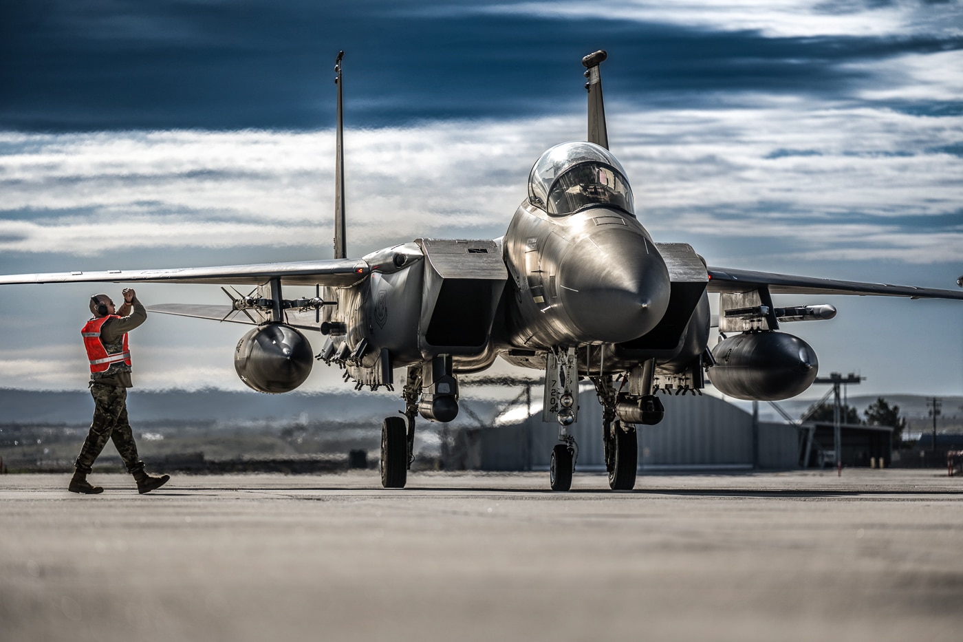 United States Air Force maintenance personnel and ground crew recovering McDonnell Douglas F-15E Strike Eagle tactical fighter after training mission at Gowen Field Idaho during Exercise Double Barrel. The twin-engine multirole combat aircraft undergoes post-flight inspection with airmen checking aircraft systems, landing gear, engines, and weapons stations. F-15E maintenance operations involve crew chiefs, avionics specialists, weapons loaders, and aircraft mechanics ensuring Strike Eagles remain mission capable for subsequent sorties. The all-weather tactical fighter features complex systems including AN/APG-70 radar, LANTIRN targeting pods, Pratt Whitney F100 turbofan engines, and electronic warfare suites requiring specialized maintenance procedures. Exercise Double Barrel provides realistic training environment for both flight crews and maintenance teams supporting F-15E operations at forward operating locations. Air Force ground personnel conduct inspections of conformal fuel tanks, flight control surfaces, hydraulic systems, and engine components after each Strike Eagle mission. Gowen Field Idaho hosts Air National Guard units and active duty squadrons for training exercises simulating deployed operations requiring rapid aircraft turnaround between missions.