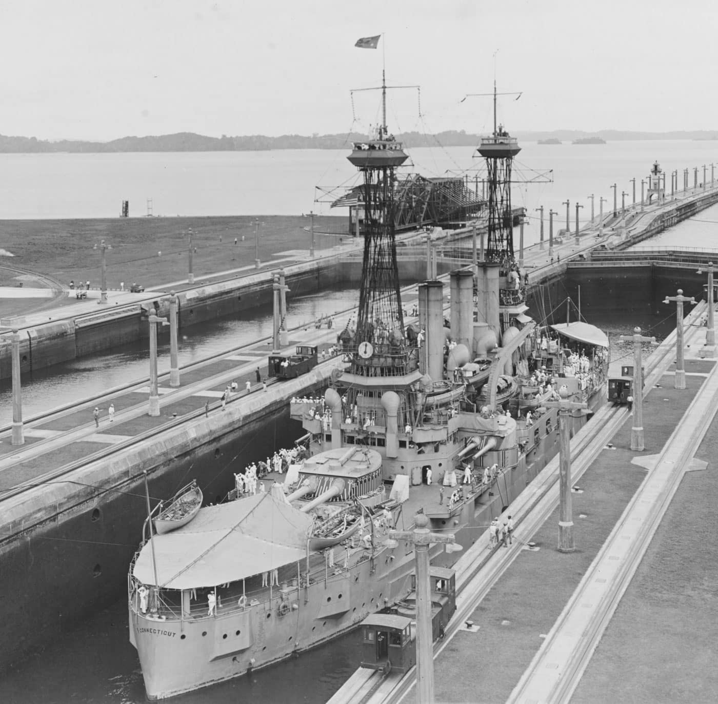 USS Connecticut American battleship transiting the Panama Canal, one of six Connecticut-class pre-dreadnought battleships that were obsolete immediately upon commissioning between 1906 and 1908 due to the revolutionary HMS Dreadnought launching before most entered service. The Connecticut-class United States battleships consisted of USS Connecticut BB-18, USS Louisiana BB-19, USS Vermont BB-20, USS Kansas BB-21, USS Minnesota BB-22, and USS New Hampshire BB-25, representing the last American pre-dreadnought battleships commissioned as the world entered the all-big-gun dreadnought era. These six vessels featured traditional mixed-caliber armament with both large and small guns, a design philosophy that became instantly obsolete when HMS Dreadnought demonstrated the superiority of uniform heavy gun batteries in 1906. The photograph shows USS Connecticut navigating through the Panama Canal, demonstrating how American battleships utilized this critical waterway to transit between Atlantic and Pacific oceans, significantly enhancing United States Navy operational flexibility. Despite being brand new when commissioned, the Connecticut-class pre-dreadnought battleships were immediately outdated and served in much the same limited roles as earlier Virginia-class and other pre-dreadnought vessels during World War I and afterwards. All six Connecticut-class battleships were scrapped by 1924, victims of both their obsolete mixed-caliber design and the Washington Naval Treaty that forced the United States to eliminate older capital ships to comply with treaty limitations. This image captures USS Connecticut during canal transit operations, showcasing how even obsolete American battleships contributed to training, power projection, and maintaining naval presence during the transition from pre-dreadnought to dreadnought-type vessels. The Connecticut-class represents the unfortunate timing of American battleship construction when the United States Navy continued building older designs even as the dreadnought revolution transformed naval architecture worldwide, resulting in vessels that were outdated before they could contribute meaningfully to fleet operations.