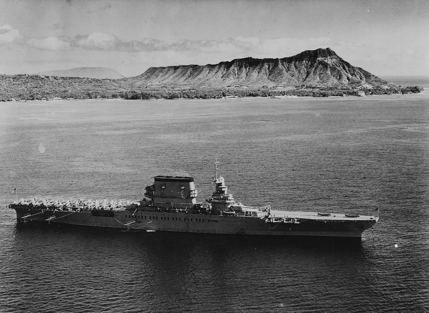 USS Lexington CV-2 steaming off Honolulu, Oahu, Hawaii with Diamond Head visible in the background on February 2, 1933 during peacetime naval operations. Lady Lex operated from Pearl Harbor throughout the 1930s conducting extensive naval exercises to develop and refine carrier aviation tactics. USS Lexington aircraft carrier had participated in simulated surprise attacks on Pearl Harbor during Grand Joint Exercise No. 4 in February 1932, one year before this photograph was taken. The Lexington CV-2 displaced 36,000 tons on the converted Lexington-class battlecruiser hull featuring a 901-foot flight deck operating 86 aircraft. USS Lexington and sister ship Saratoga CV-3 were the largest aircraft carriers in the world when this photograph was taken, pioneering carrier warfare doctrine from Hawaiian waters. Lady Lex was commissioned in late 1927 under the Washington Naval Treaty that allowed battlecruiser conversions to carriers with displacement exceeding standard treaty limits. The Lexington carrier would conduct another simulated attack on Pearl Harbor during Fleet Problem XIX drills in March 1938, exercises that proved prophetic when Japanese forces attacked in December 1941. USS Lexington CV-2 earned two battle stars during World War II Pacific operations before being lost at the Battle of Coral Sea in May 1942.