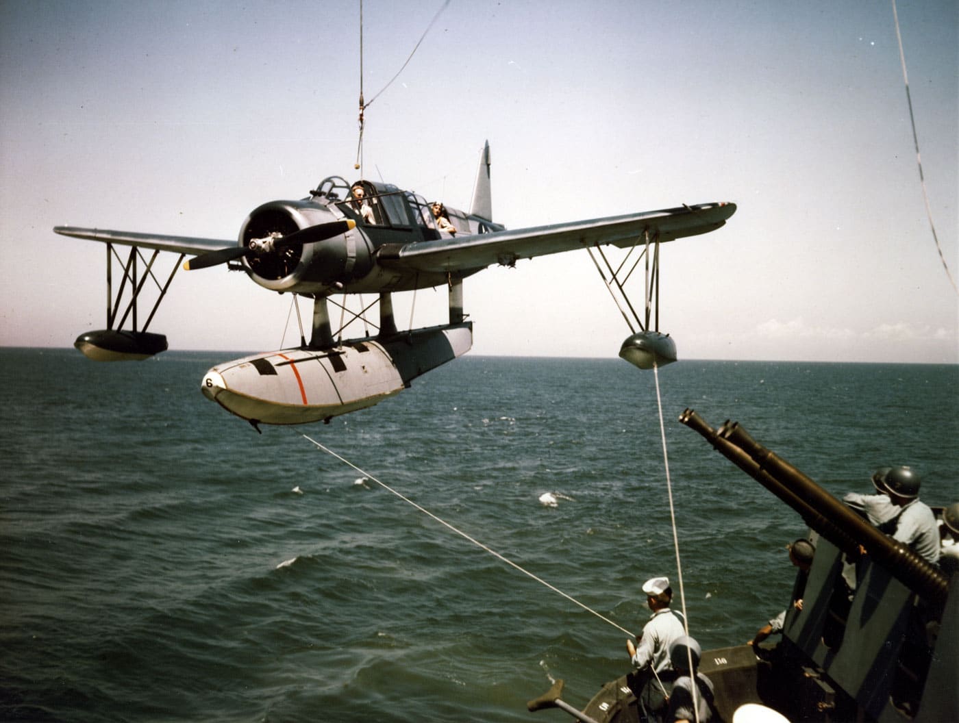 USS Missouri BB-63 American fast battleship hoisting OS2U Kingfisher floatplane aboard the ship, demonstrating how Iowa-class battleships carried scout aircraft for reconnaissance, observation, and spotting gunfire during combat operations to extend their effectiveness and maintain relevance in the carrier-dominated era. The Iowa-class United States fast battleships including USS Missouri BB-63, USS Iowa BB-61, USS New Jersey BB-62, and USS Wisconsin BB-64 all utilized aircraft like the OS2U Kingfisher for fire control observation, helping direct the accurate fire from their nine 16-inch guns during shore bombardment missions. Scout floatplanes provided Iowa-class battleships with extended reconnaissance capabilities and critical fire spotting services, allowing battleship gunnery officers to accurately engage targets beyond visual range during World War II, Korean War, and later Gulf War operations. The photograph shows USS Missouri recovering her OS2U Kingfisher floatplane after operations, illustrating the combined arms approach that integrated aviation assets with traditional battleship capabilities to maintain combat effectiveness as naval warfare evolved. USS Missouri BB-63 holds special historical significance as the site where Japan formally surrendered on September 2, 1945 ending World War II, and subsequently served during the Korean War and after 1980s modernization during the Gulf War before becoming a museum ship. The Iowa-class battleships represented the most advanced American battleships ever built, serving from World War II through the Cold War with multiple modernizations adding capabilities like Harpoon missiles, Tomahawk cruise missiles, and Phalanx systems alongside the traditional 16-inch guns. Aircraft like the OS2U Kingfisher extended battleship combat effectiveness by providing over-the-horizon reconnaissance, damage assessment, and fire correction services that helped Iowa-class vessels deliver accurate devastating shore bombardment supporting ground forces. All four Iowa-class fast battleships were decommissioned in the 1990s and now serve as museum ships preserving naval history: USS Iowa in Los Angeles, USS New Jersey in Camden, USS Wisconsin in Norfolk, and USS Missouri in Pearl Harbor alongside the USS Arizona memorial.