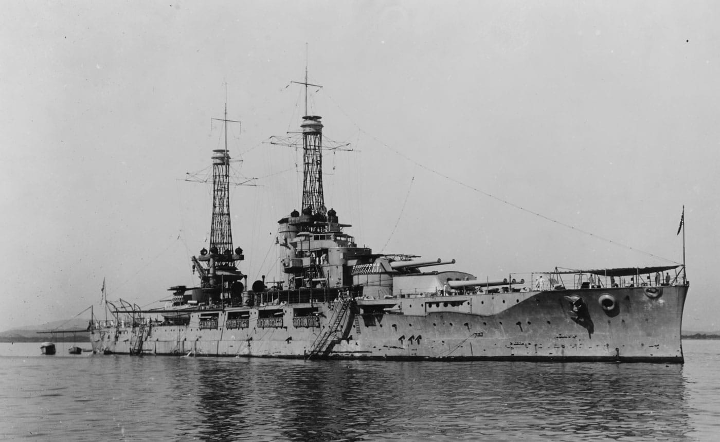 USS Nevada BB-36 American standard-type battleship photographed in Guantanamo Bay, Cuba, circa January 1920, representing one of two Nevada-class vessels that introduced the standard-type battleship philosophy to the United States Navy. The Nevada-class United States battleships consisted of USS Nevada BB-36 and USS Oklahoma BB-37, both displacing more than 27,000 tons with 13.5-inch armor belts and equipped with four turrets mounting ten 14-inch guns total. These standard-type battleships featured common tactical speeds around 21 knots with tight turning circles for coordinated fleet maneuvering, establishing design principles that would guide American battleship construction through multiple classes. USS Nevada BB-36 was heavily damaged at Pearl Harbor on December 7, 1941, being struck by an estimated six to ten bombs and at least one torpedo during the Japanese surprise attack on the United States Pacific Fleet. Through heroic efforts of officers and crew, USS Nevada was able to get underway during the attack and made for shallower water when her sinking seemed imminent, beaching at Hospital Point and preventing total loss. Because of these efforts, the Nevada-class battleship was refloated, repaired, and upgraded, returning to provide support during the Aleutian Islands campaign, at Normandy during Operation Neptune, in Operation Dragoon, at Iwo Jima, and at Okinawa. Her sister ship USS Oklahoma BB-37 did not survive Pearl Harbor, being struck by three Japanese torpedoes in the opening minutes with between two and five additional torpedoes hitting as she capsized, killing more than 400 men including the three Barber brothers and the first United States chaplain to die in World War II, Father Aloysius Schmitt. By June 1943, USS Oklahoma was righted but was too extensively damaged for repair, stripped of all working guns and machinery, decommissioned in 1944, and sold for scrap after the war ended.