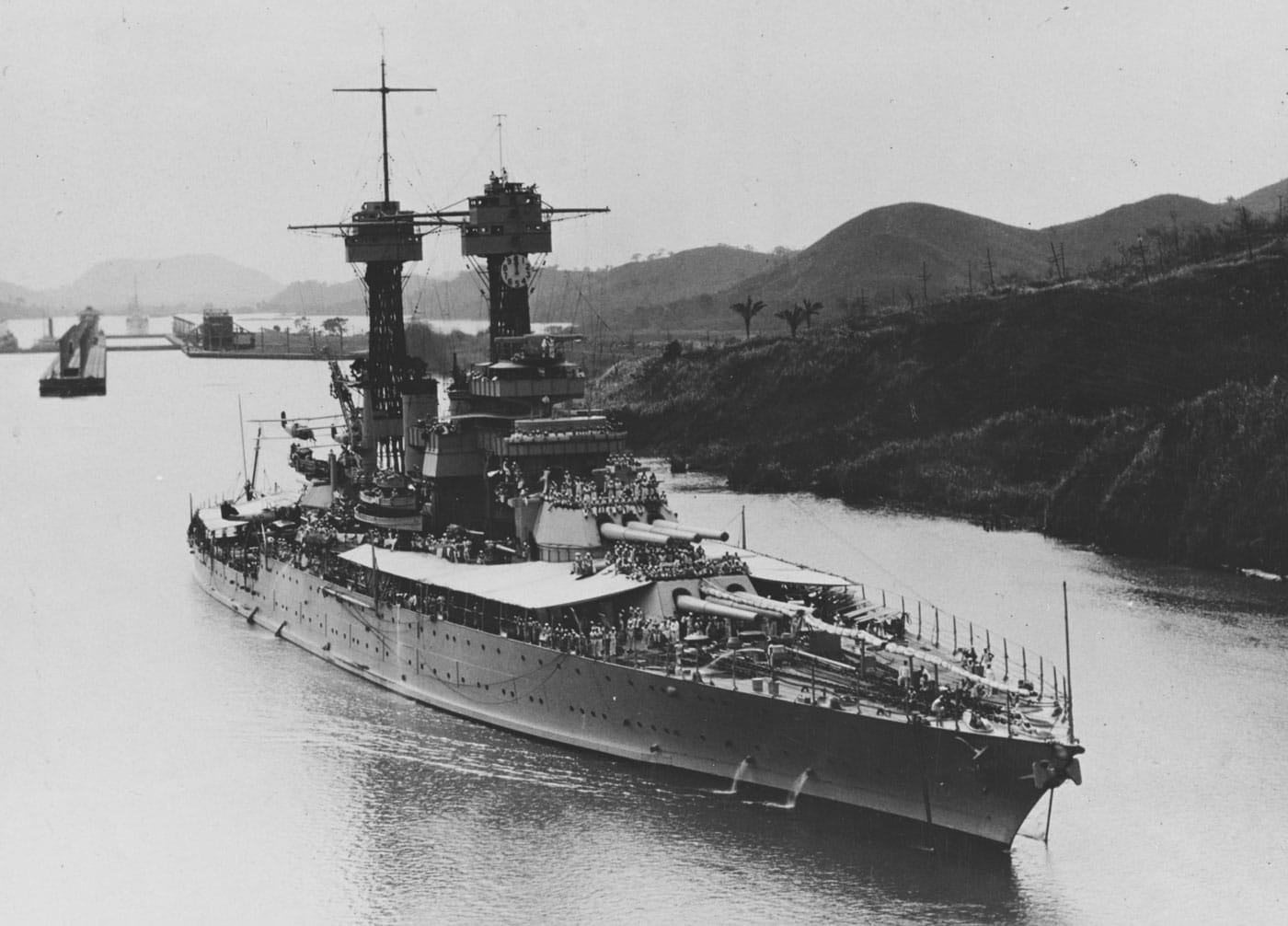 USS Tennessee BB-43 American standard-type battleship transiting the Panama Canal during the 1930s, representing one of two Tennessee-class vessels that featured incremental improvements over the New Mexico-class battleships including elevated main batteries for improved range and enhanced underwater protection. The Tennessee-class United States battleships consisted of USS Tennessee BB-43 and USS California BB-44, both products of World War I construction that would prove their worth during World War II operations throughout the Pacific Theater. On December 7, 1941, both Tennessee-class standard-type battleships were moored in Pearl Harbor when Japanese forces launched their devastating surprise attack on the United States Pacific Fleet. Both USS Tennessee and USS California engaged enemy aircraft during the attack and both were hit multiple times by bombs and torpedoes in return, suffering significant damage and casualties. However, both Tennessee-class battleships survived the sneak attack and went on to repay Japanese forces multiple times over through extensive combat operations throughout the Pacific campaign. USS Tennessee BB-43 and USS California BB-44 both earned ten battle stars during World War II, demonstrating the combat effectiveness and resilience of American standard-type battleships despite being older designs compared to the North Carolina-class, South Dakota-class, and Iowa-class fast battleships. The photograph shows USS Tennessee navigating through the Panama Canal, illustrating how American battleships utilized this strategic waterway to transit between Atlantic and Pacific oceans, significantly enhancing United States Navy operational flexibility and power projection capabilities. Sadly, both Tennessee-class battleships were sold for scrap in 1959, victims of post-war naval reductions as the United States transitioned to a smaller peacetime fleet focused on aircraft carriers and nuclear-powered vessels. As standard-type battleships, the Tennessee-class vessels embodied the design philosophy featuring common tactical speeds around 21 knots with tight turning circles enabling coordinated fleet maneuvering that characterized American battleship construction from the Nevada-class through the Colorado-class super-dreadnoughts.