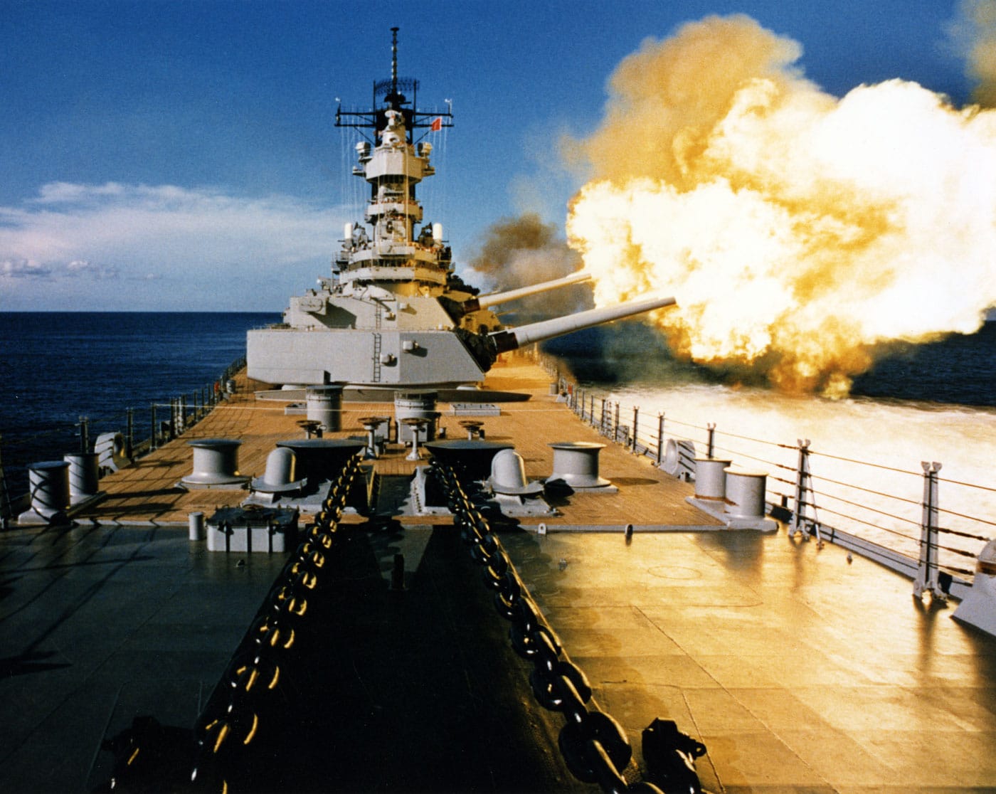 USS Wisconsin BB-64 American fast battleship firing a full broadside to port with her 16-inch 50-caliber and 5-inch 38-caliber guns circa 1988-1991, demonstrating the devastating combined firepower of modernized Iowa-class battleships during their final period of Cold War and Gulf War service following comprehensive Reagan-era modernization. USS Wisconsin BB-64 was one of four Iowa-class United States fast battleships including USS Iowa BB-61, USS New Jersey BB-62, and USS Missouri BB-63, all serving from World War II through multiple modernizations culminating in the ambitious 1980s Reagan administration program that transformed these vessels into modern multi-role capital ships. The dramatic photograph shows USS Wisconsin firing both her massive 16-inch main battery guns and secondary 5-inch dual-purpose guns simultaneously, illustrating the overwhelming firepower that made Iowa-class battleships formidable assets combining traditional naval gunfire with modern precision-guided missiles. During the 1980s modernization, all four Iowa-class fast battleships were extensively upgraded with cutting-edge weapons systems including Harpoon anti-ship missiles for engaging surface targets, Tomahawk cruise missiles capable of precision strikes against land targets, and Phalanx close-in weapon systems providing last-line defense against incoming missiles and aircraft. The modernized Iowa-class battleships retained their powerful 16-inch guns capable of firing from ranges exceeding 20 miles, complemented by 5-inch dual-purpose guns for anti-aircraft and surface engagements, creating a layered weapons system that could engage threats from over-the-horizon distances down to point-blank range. USS Wisconsin BB-64 served during the Gulf War in 1991, firing Tomahawk cruise missiles during the opening salvos of Operation Desert Storm and providing accurate shore bombardment supporting coalition ground forces, demonstrating the continued relevance of battleship capabilities in modern warfare. The Iowa-class battleships formed Surface Action Groups or Battleship Battle Groups during the 1980s-90s, serving as powerful symbols of American naval might and providing capabilities that complemented carrier strike groups and amphibious ready groups throughout global operations. All four Iowa-class fast battleships were permanently decommissioned in the 1990s after the Cold War ended and now serve as museum ships: USS Iowa in Los Angeles, USS New Jersey in Camden, USS Wisconsin in Norfolk, and USS Missouri in Pearl Harbor.