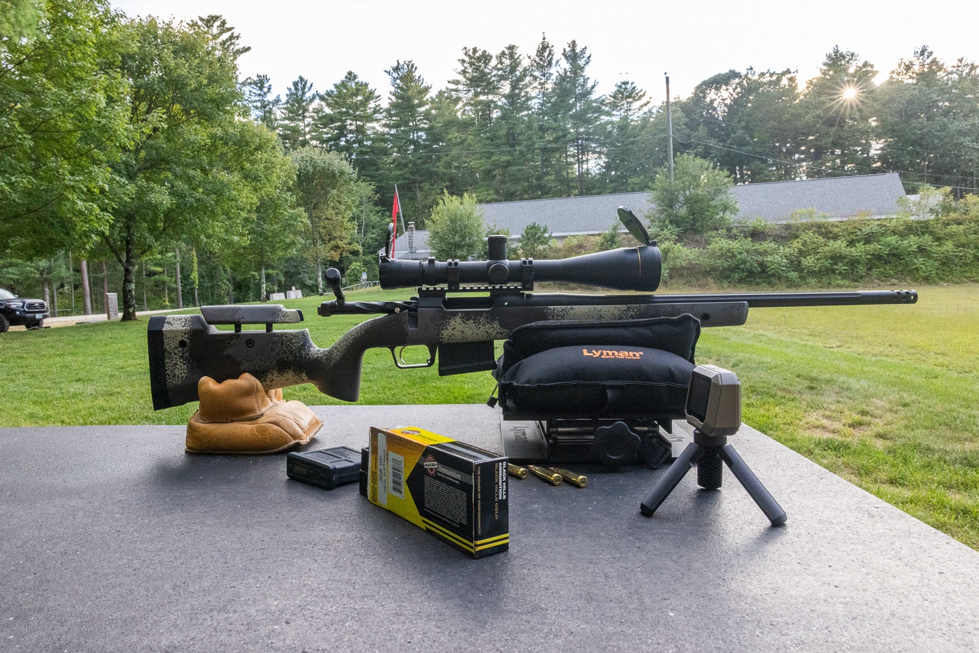 Benchrest shooting setup showing rifle and Black Hills Gold .308 Winchester 168-grain Hornady ELD Match ammunition ready for 100 yard accuracy testing. Black Hills .308 ammo boxes visible with precision rifle positioned on sandbags for group shooting. Testing configuration for Black Hills Gold 308 cartridges loaded with 168-gr ELD Match bullets at concrete bench. Rifle supported by front and rear bags during Black Hills Ammunition .308 Win evaluation with 168 grain projectiles. Shooting station arranged for accuracy testing Black Hills Gold .308 168-gr ELD ammunition at 100 yards. Black Hills .308 Winchester ammo with Hornady ELD Match bullets positioned for benchrest shooting session. Proper rifle support and Black Hills Gold 308 ammunition setup ensures consistent results with 168 grain ELD loads. Benchrest view of testing equipment and Black Hills .308 Win cartridges with 168-gr ELD Match projectiles.