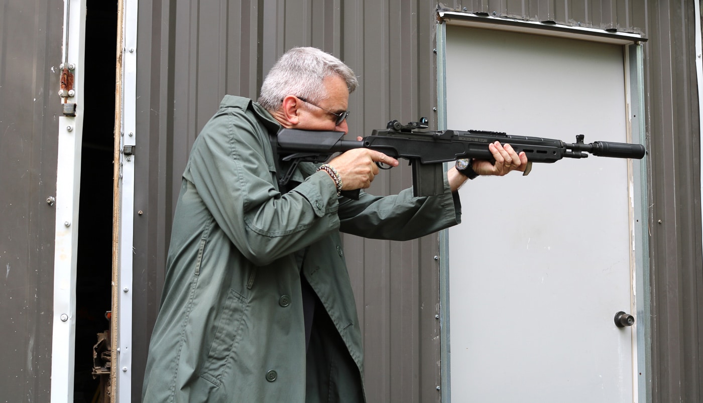 Author Will Dabbs conducting live-fire testing of Springfield Armory M1A SOCOM 16 CQB rifle equipped with Dead Air Sandman X centerfire rifle suppressor for this comprehensive suppressor review evaluation. The range session validates the Sandman X's acoustic performance on 7.62x51mm NATO platform while assessing how the Triskelion Gas Management System manages back pressure and combustion gas venting during actual shooting conditions. Testing includes supersonic .308 Winchester factory ammunition that produces unavoidable sonic crack above 1,125 feet per second as well as subsonic handloads loaded just below the sound barrier for movie-grade quiet acoustic signature. The Sandman X's Haynes 282 superalloy construction maintains structural integrity through extended shooting strings that generate extreme barrel temperatures and thermal stress typical of hard-use suppressor applications. Real-world evaluation confirms the suppressor's ability to keep noxious ammonia smell and combustion byproducts channeled forward rather than venting back toward the shooter's face, improving comfort during range sessions. The SOCOM 16's reliable piston-driven M14 action cycles consistently with the Sandman X attached, demonstrating compatibility between proven battle rifle design and modern suppressor technology. Practical testing validates manufacturer claims about reduced back pressure, effective heat dissipation, and acoustic performance that transforms ear-splitting rifle reports into sound levels comparable to nail guns when shooting into earthen backstops.