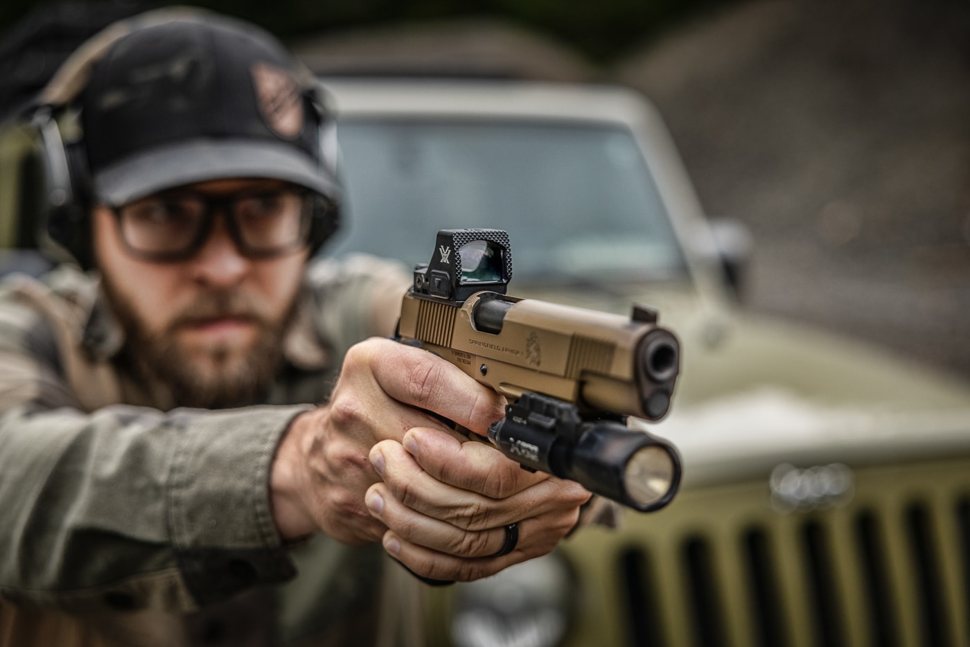 author aiming pistol with red dot sight mounted on it