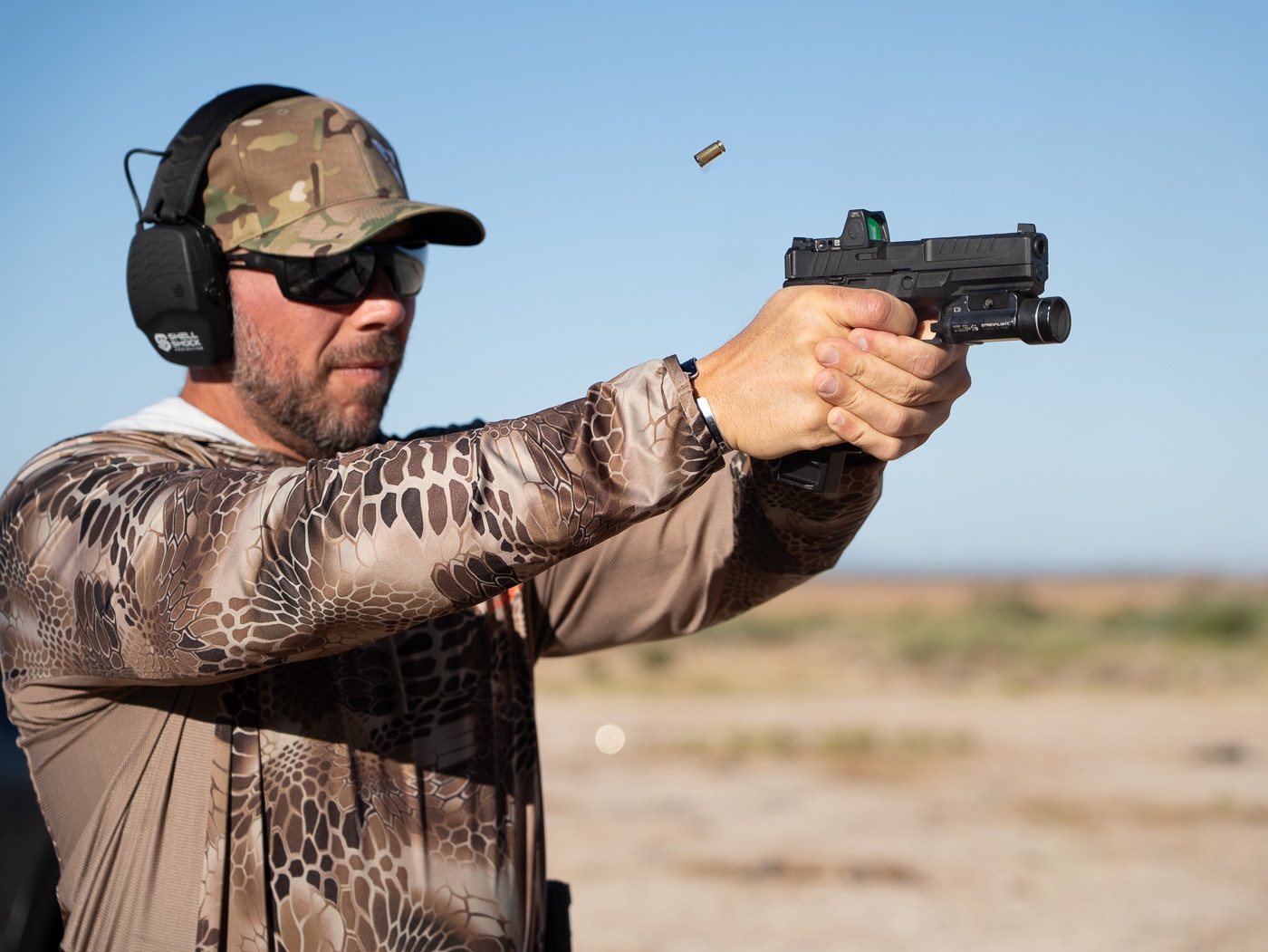 Author firing Springfield Echelon 9mm pistol during top shooting drills training session demonstrating proper technique and fundamentals on firearms range. Best shooting drills for pistol training develop marksmanship skills through structured exercises that combine accuracy work with speed and weapon manipulation practice. Echelon 9mm handgun shooting drill execution shows proper stance, grip technique, and sight alignment during live-fire training exercise. Top three shooting drills for pistol platforms test multiple fundamentals including trigger control, recoil management, breathing discipline, and follow-through consistency. Dynamic 9mm pistol training drills incorporate movement elements, reload procedures, and elevated heart rate conditions for realistic skill development. Professional firearms shooting exercises with Echelon pistol build proficiency through repetitive practice of draw presentations, target engagement, and magazine changes. Live-fire pistol drills on range develop muscle memory for consistent shooting performance under timed conditions and physical stress. Effective 9mm handgun training through structured shooting drills produces measurable improvement in accuracy, speed, and overall firearms handling capability.